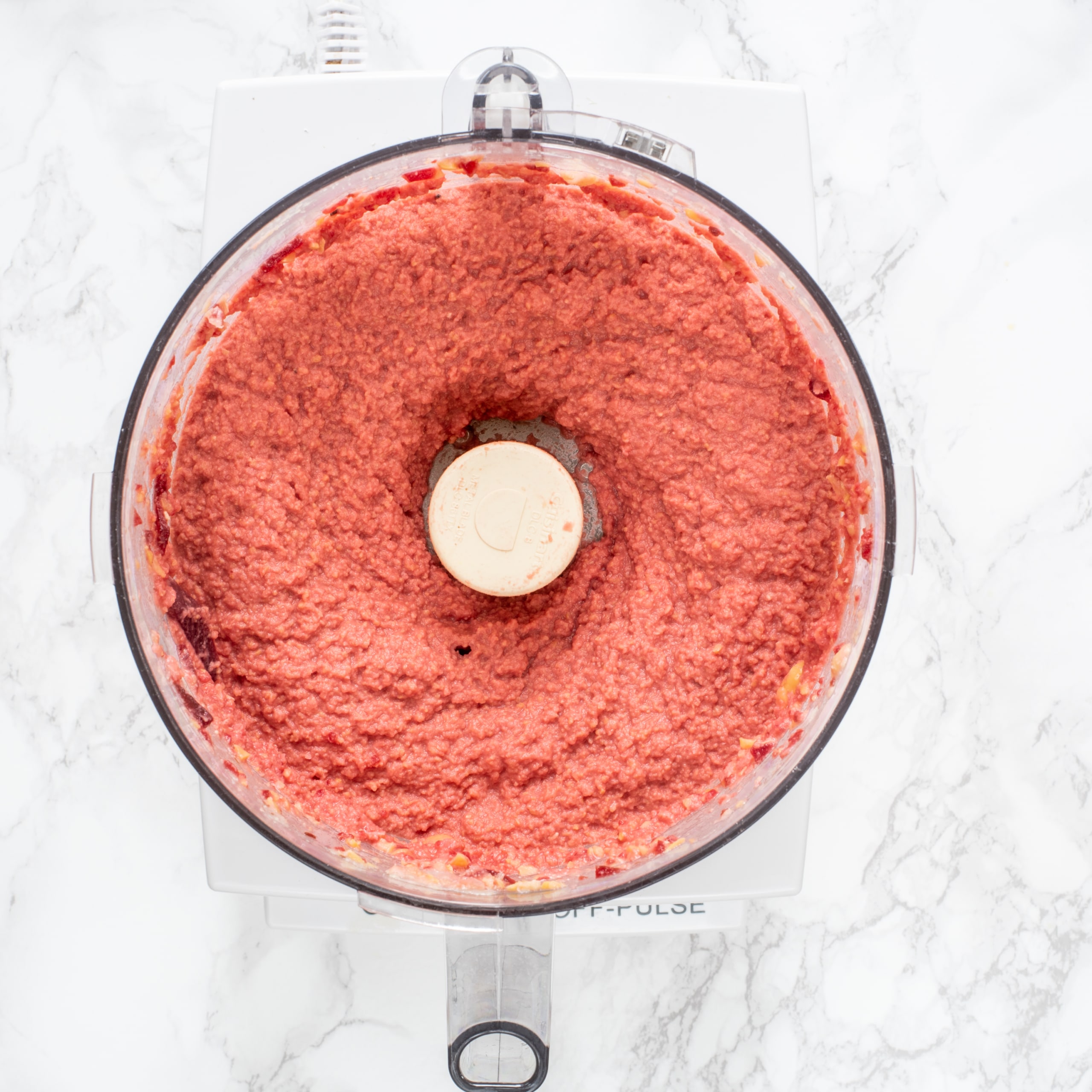 A small food processor filled with pink beet hummus.