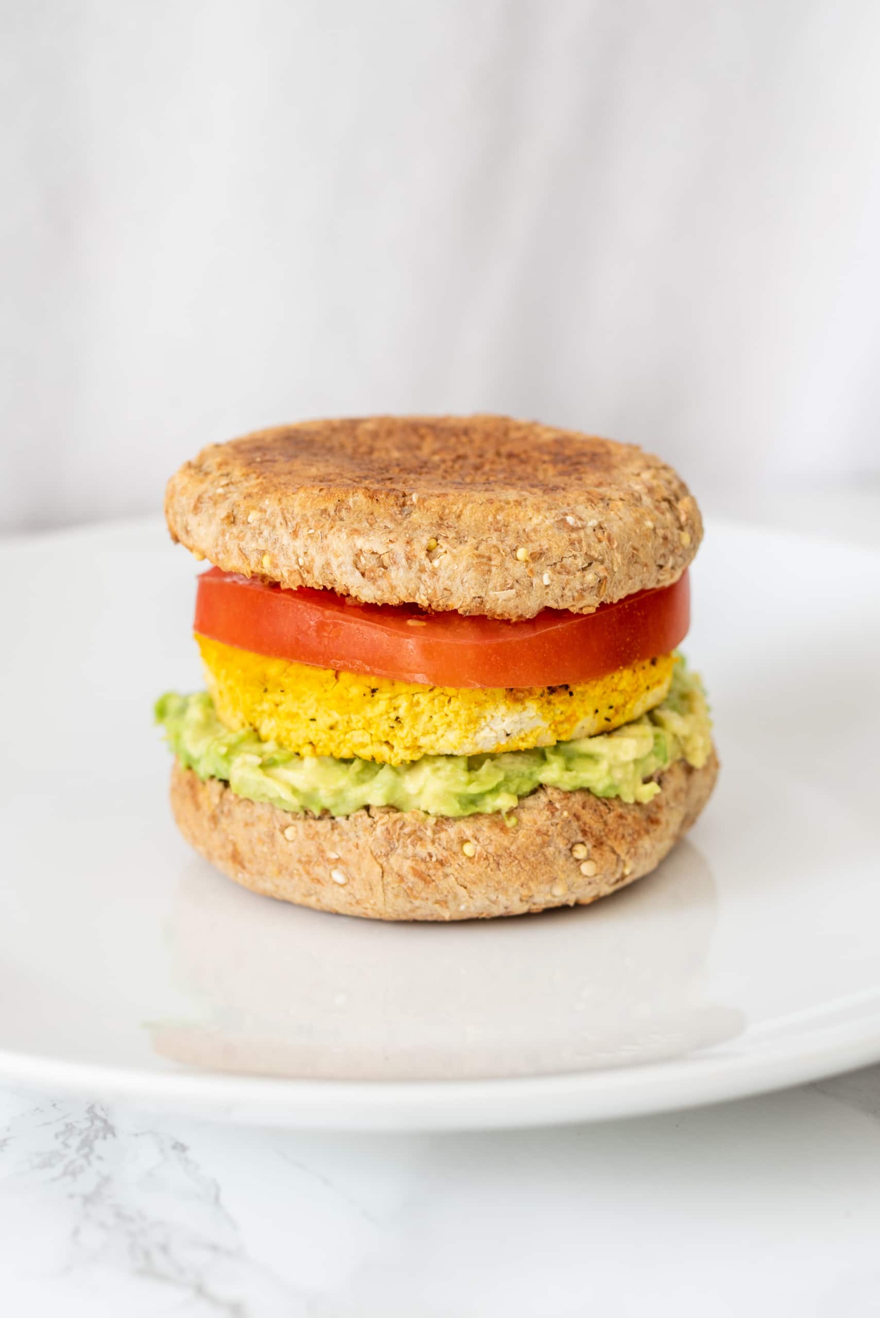 A vegan breakfast sandwich on a white plate.
