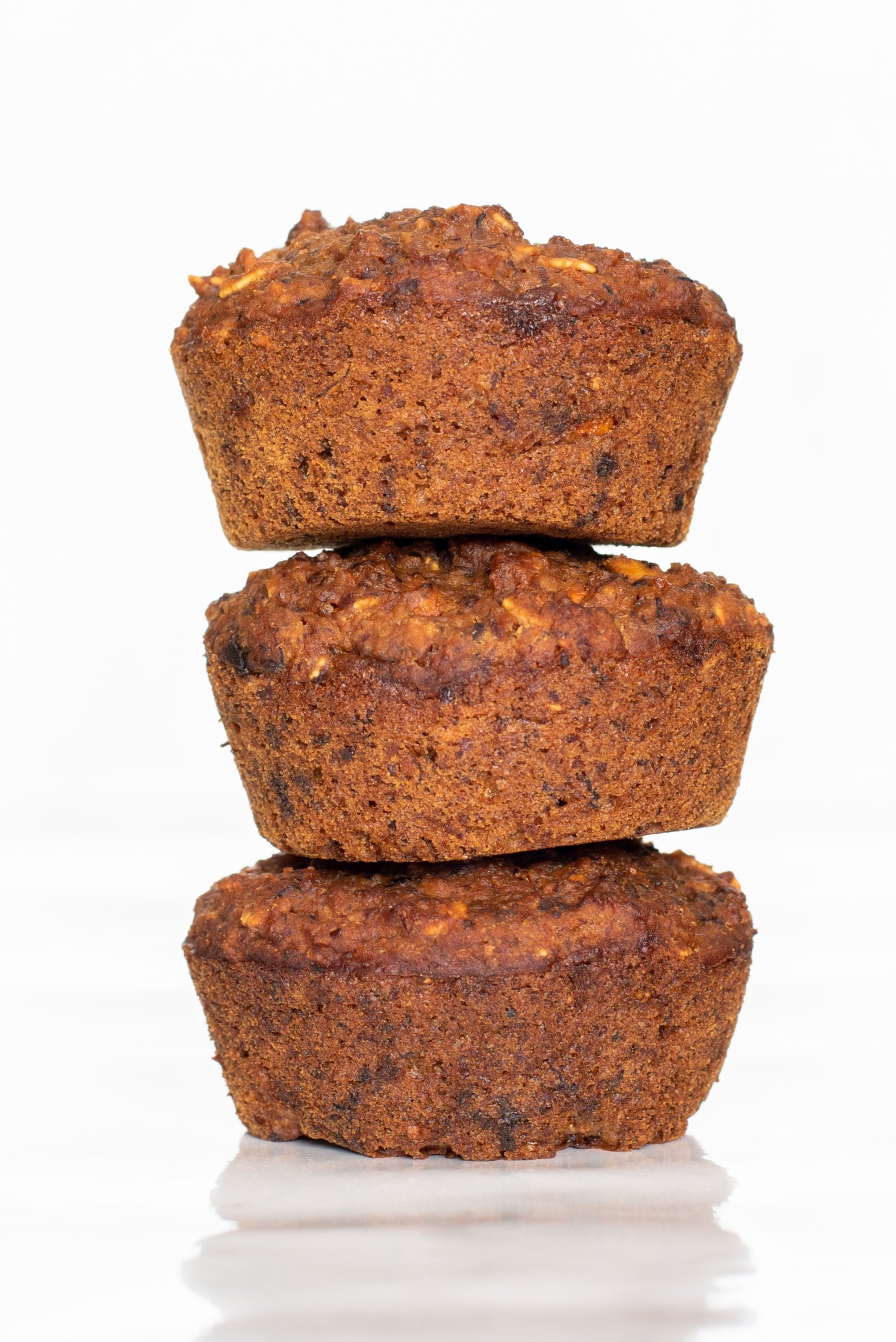Three Vegan Carrot Cake Muffins stacked on top of each other.