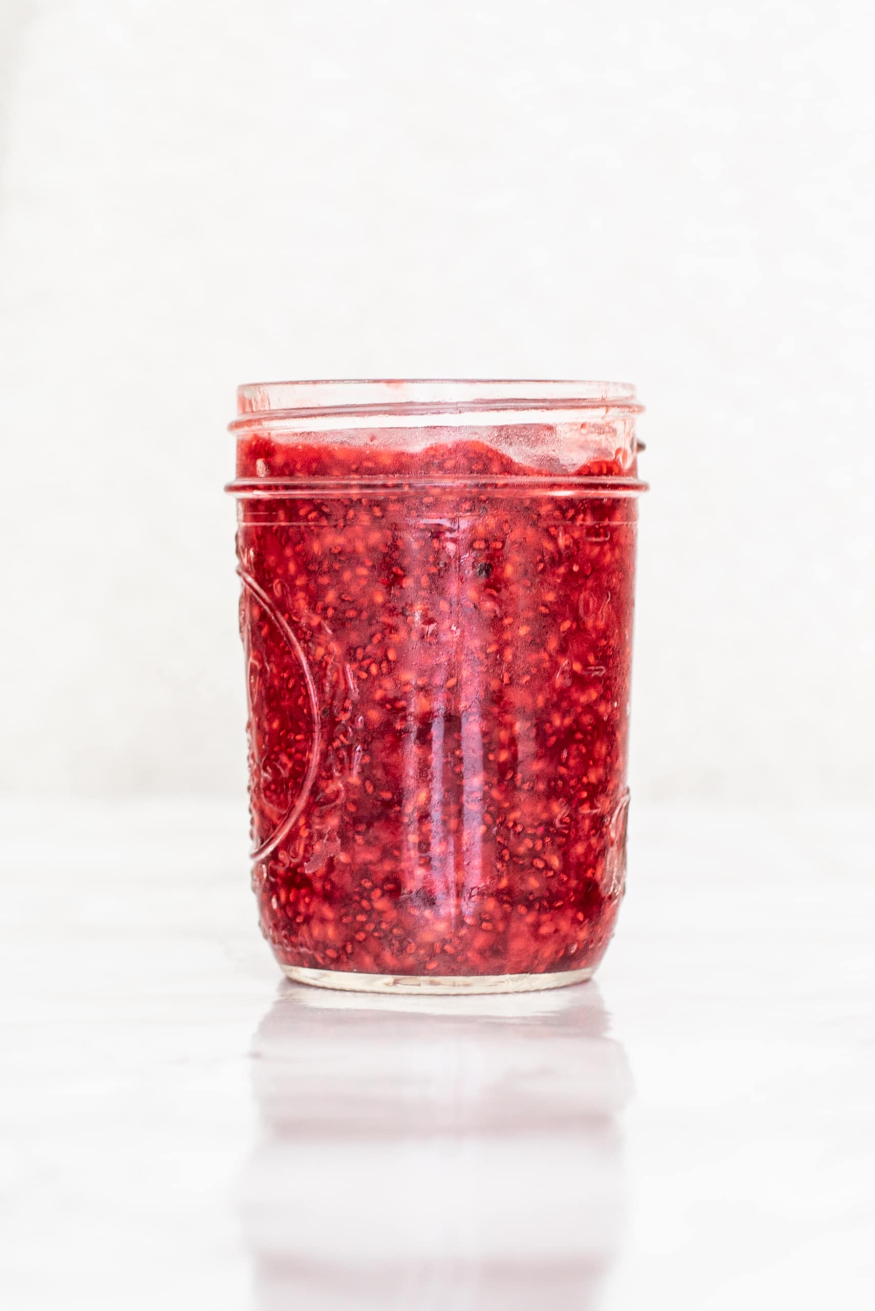 Raspberry Chia Jam in a clear glass mason jar.