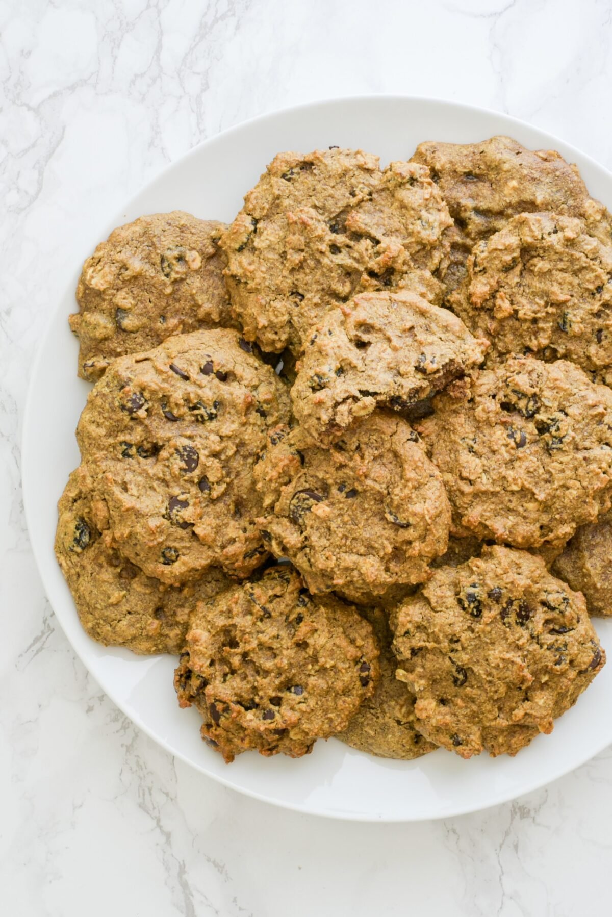 A white plate filled with oatmeal raisin cookies.