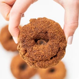 A white hand holding a cinnamon sugar doughnut.