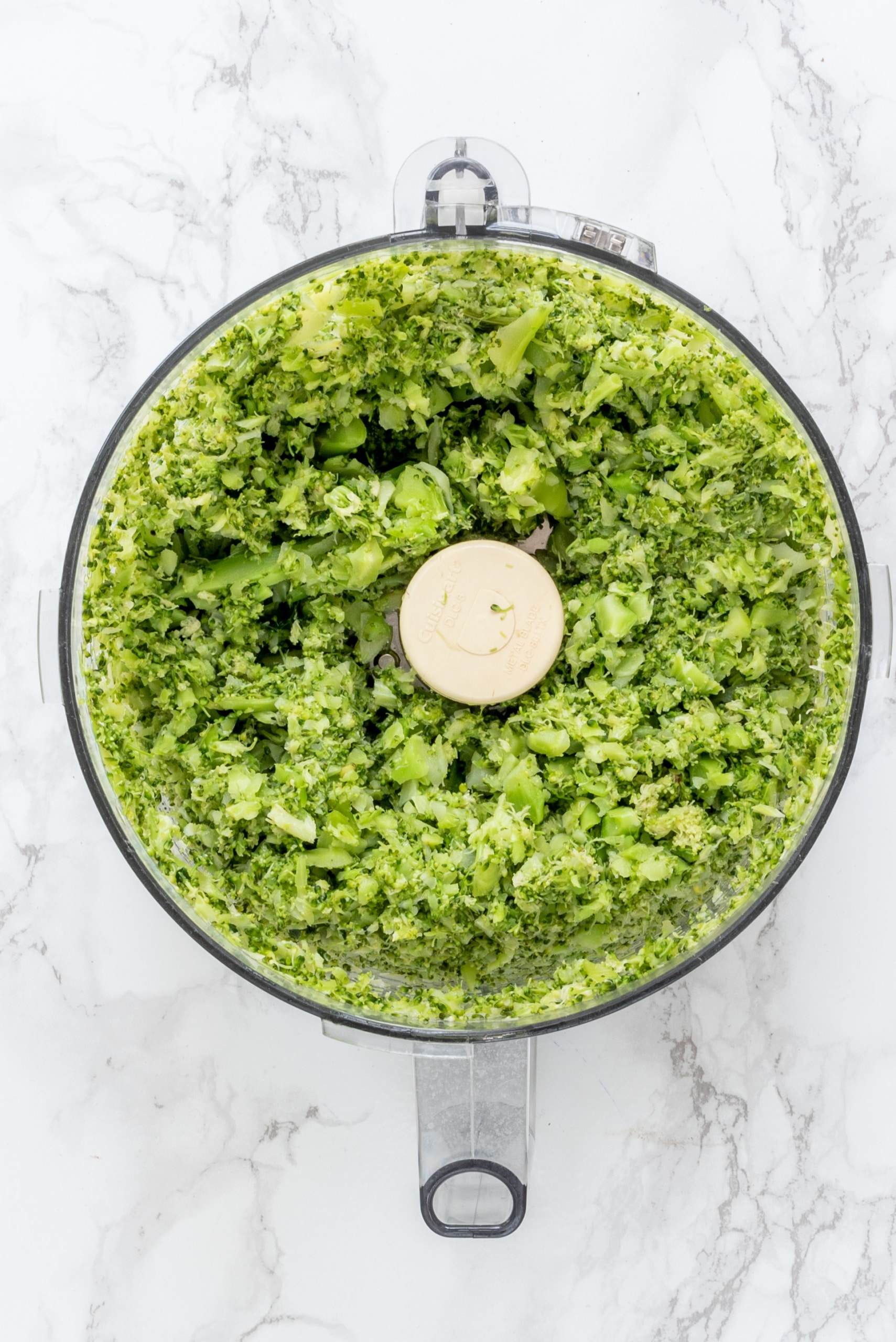 A small food processor filled with broccoli blended up.