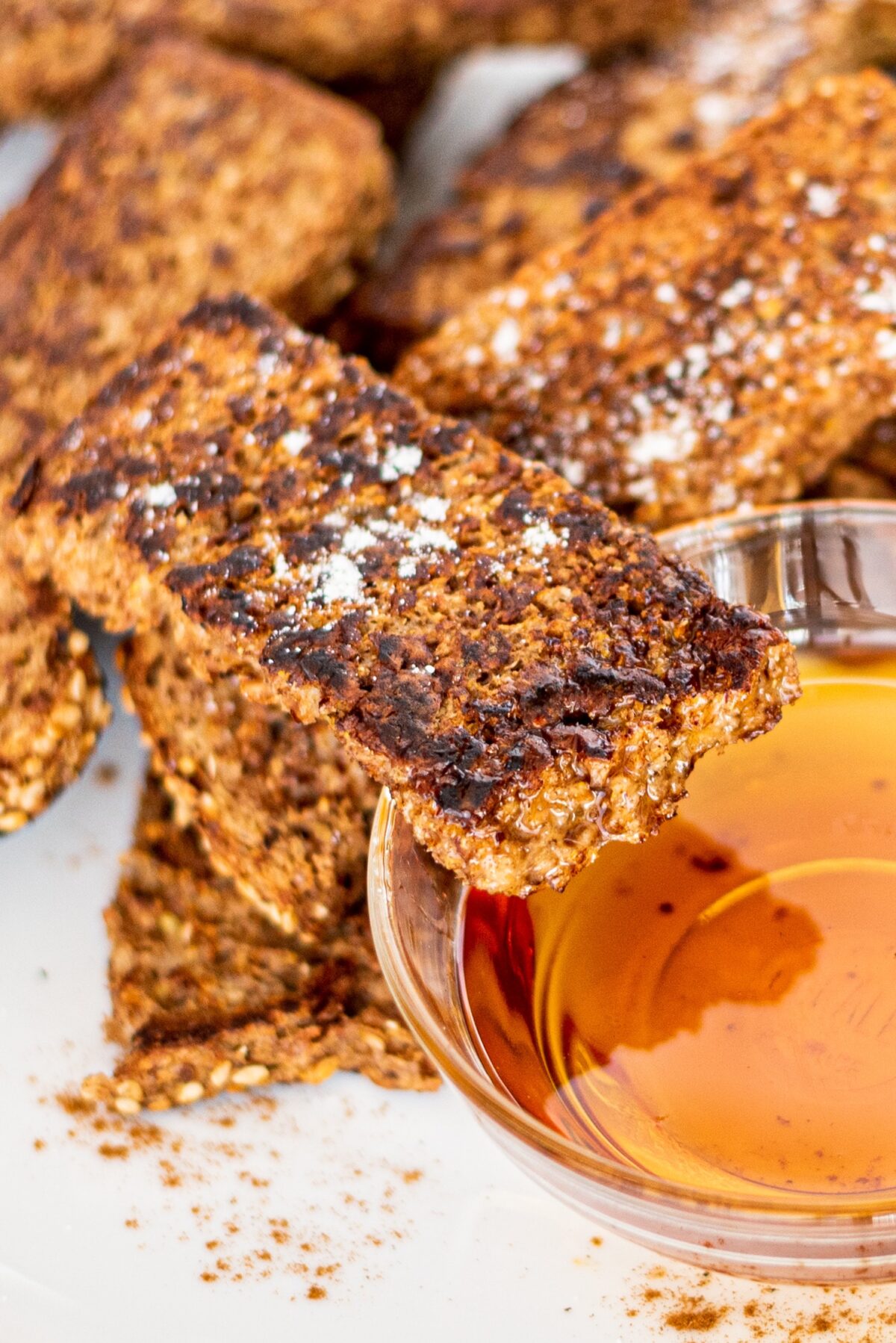 French toast sticks on a white plate and a small bowl of maple syrup.