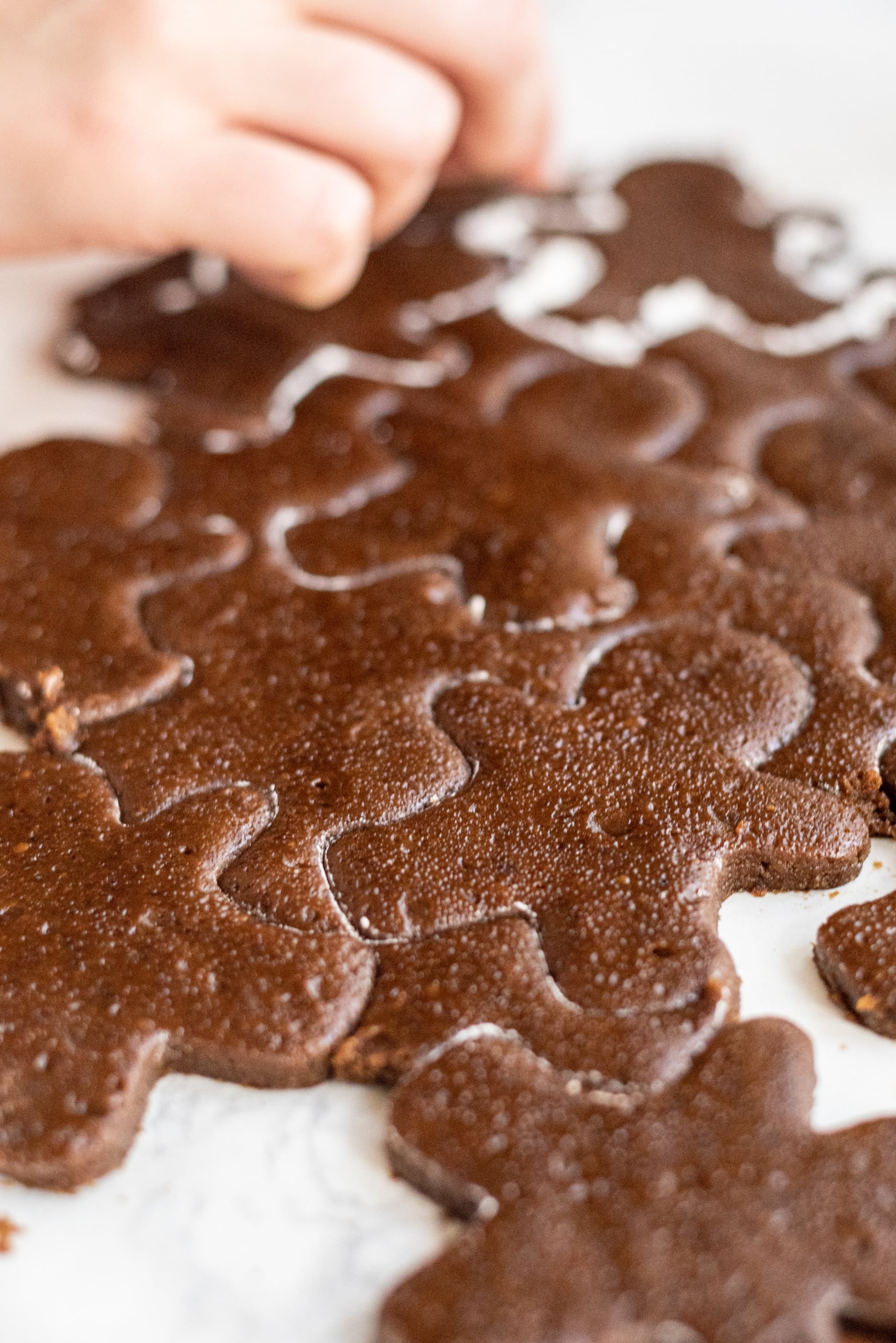 Vegan gingerbread men being cut from a sheet of gingerbread cookie dough.