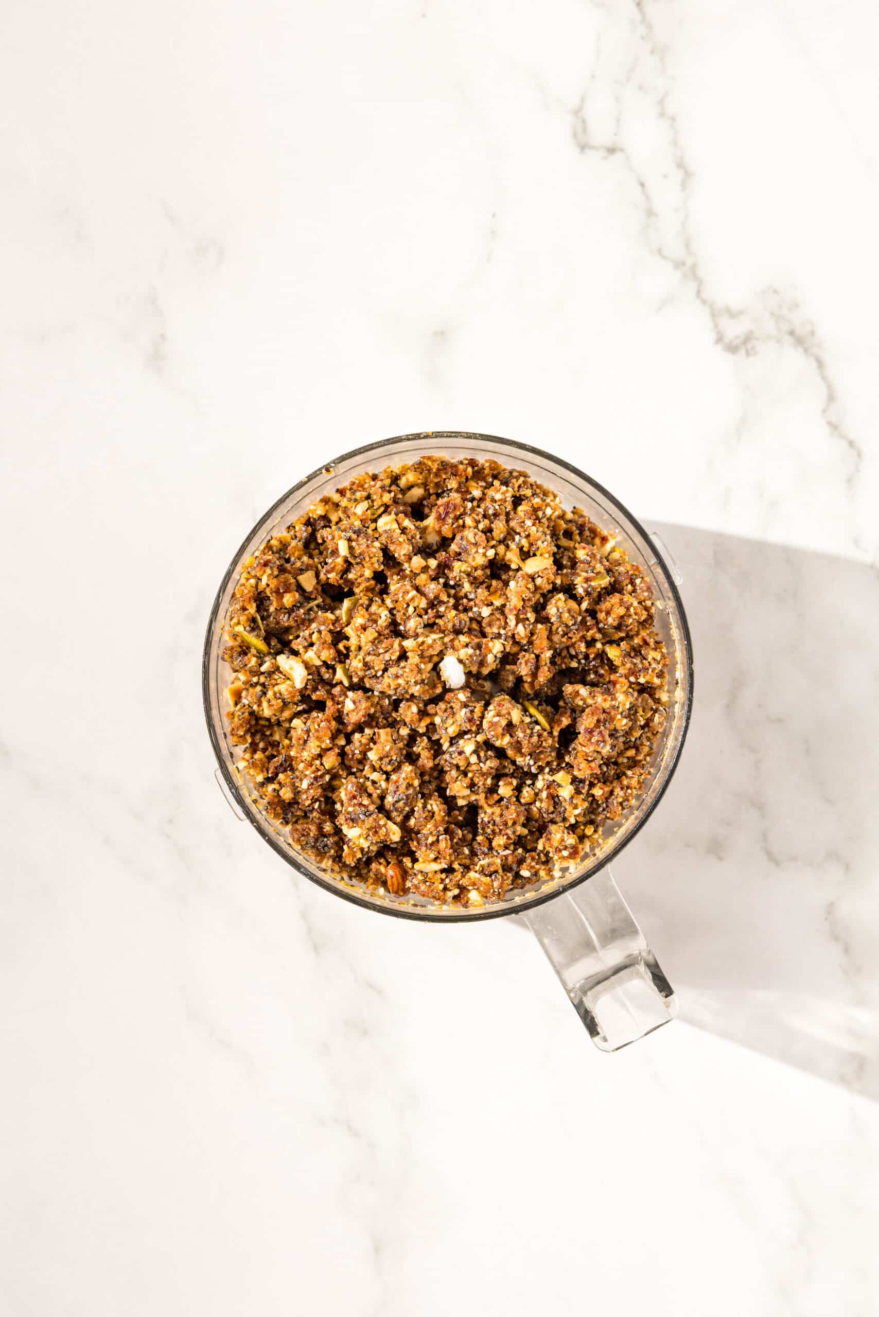 A small food processor filled with no bake vegan protein bar dough.