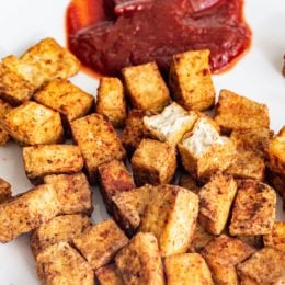 Vegan Air-Fried Tofu Nuggets on a white plate with one broken in half and a circle of ketchup.