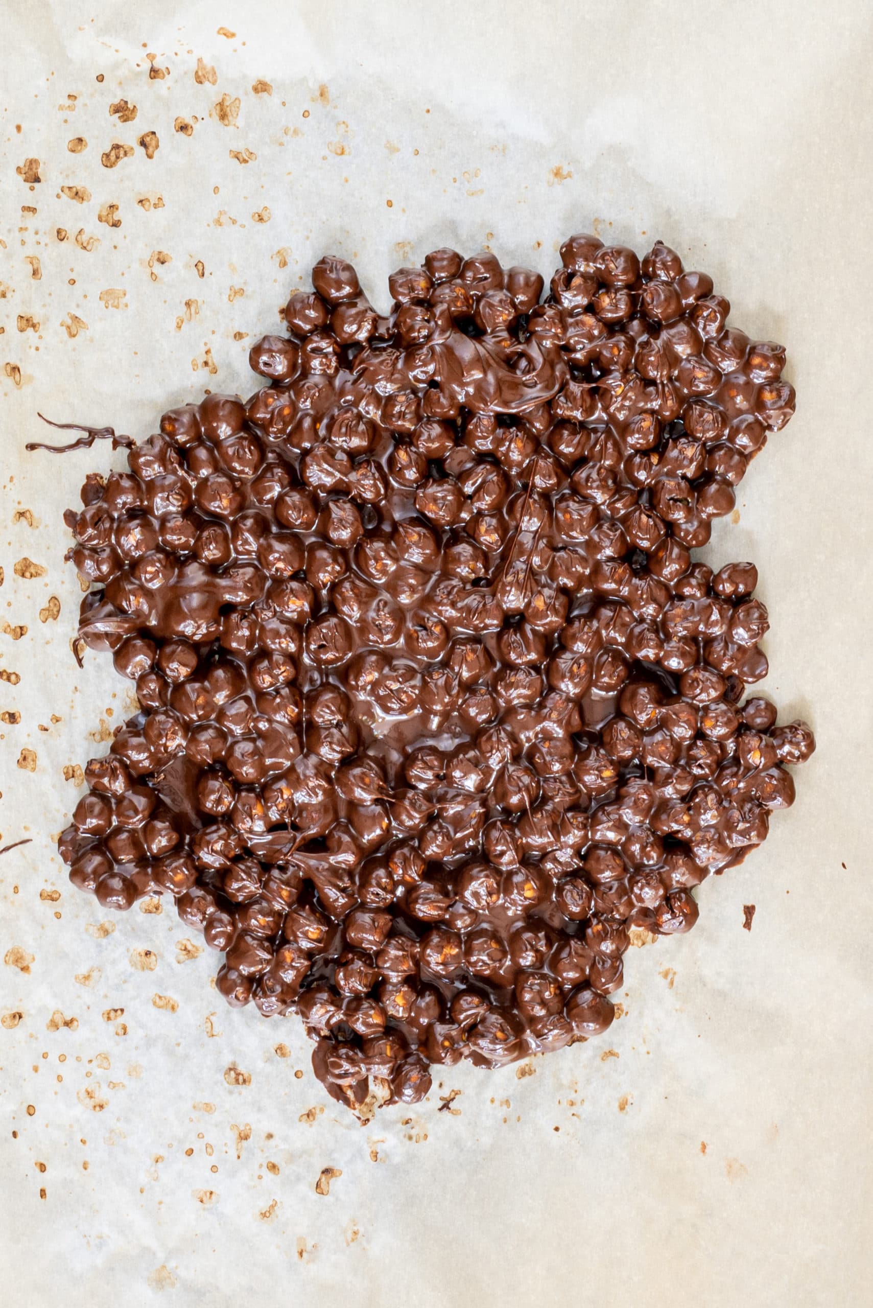 A piece of parchment paper with chocolate covered chickpeas on it.