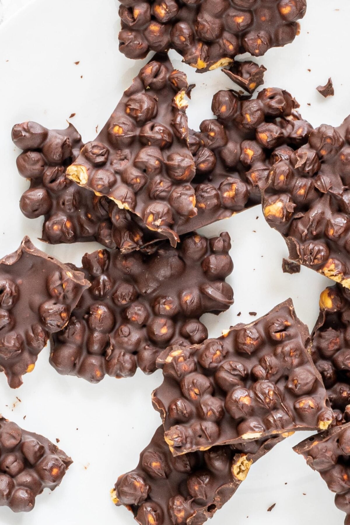 A piece of parchment paper with pieces of chocolate chickpea bark on it.