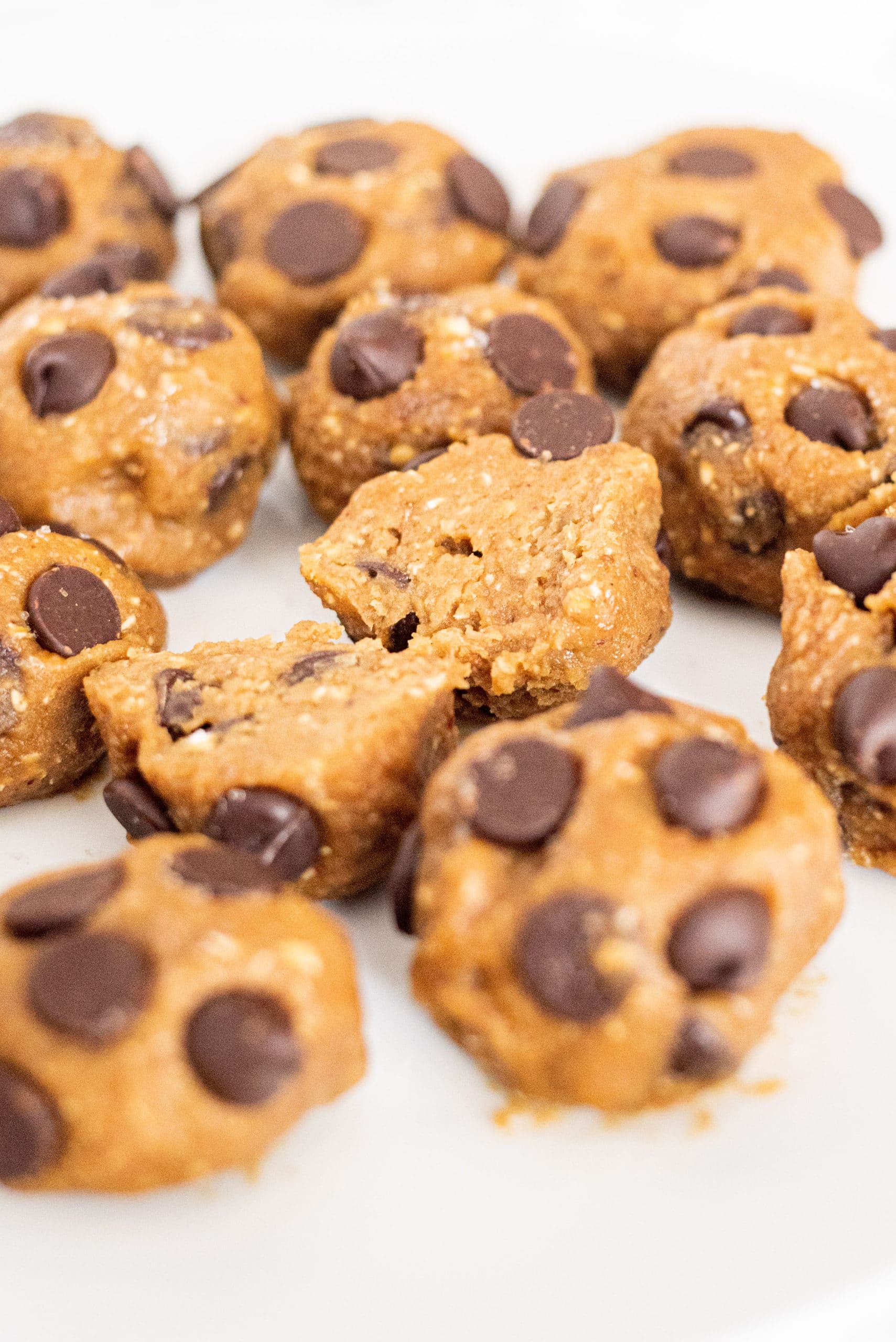 A white plate filled with chocolate chip cookie dough bites with one cut in half in the center.