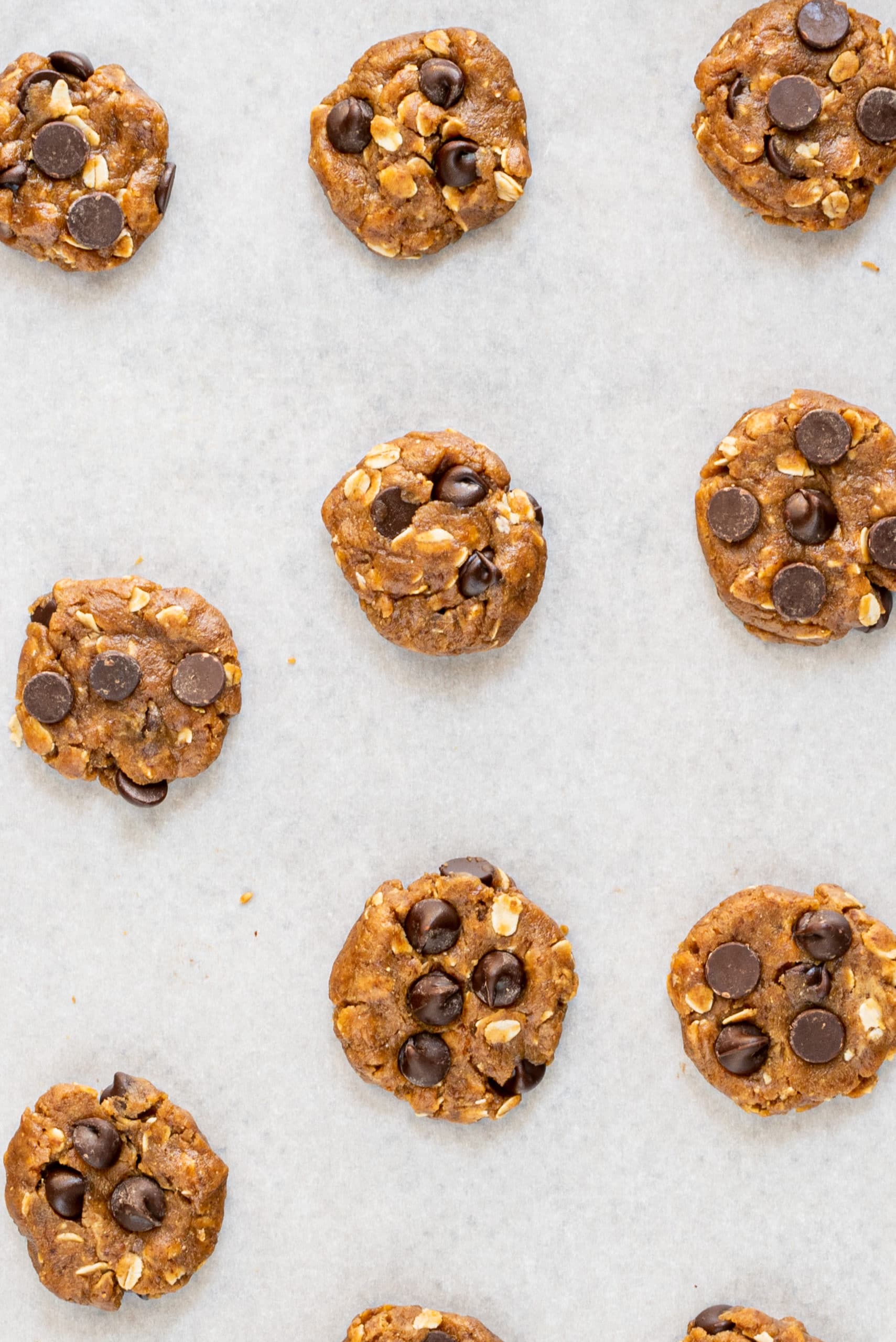 A baking sheet lined with parchment paper and unbaked chocolate chip cookies on it.