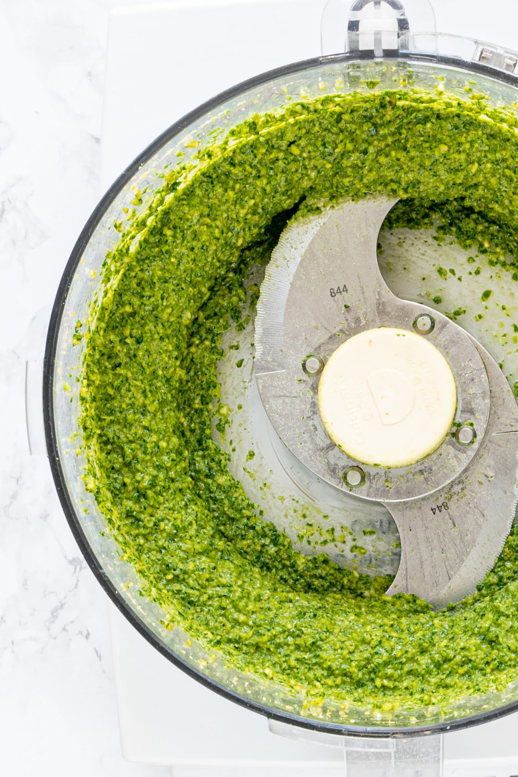 A food processor filled with green pesto.