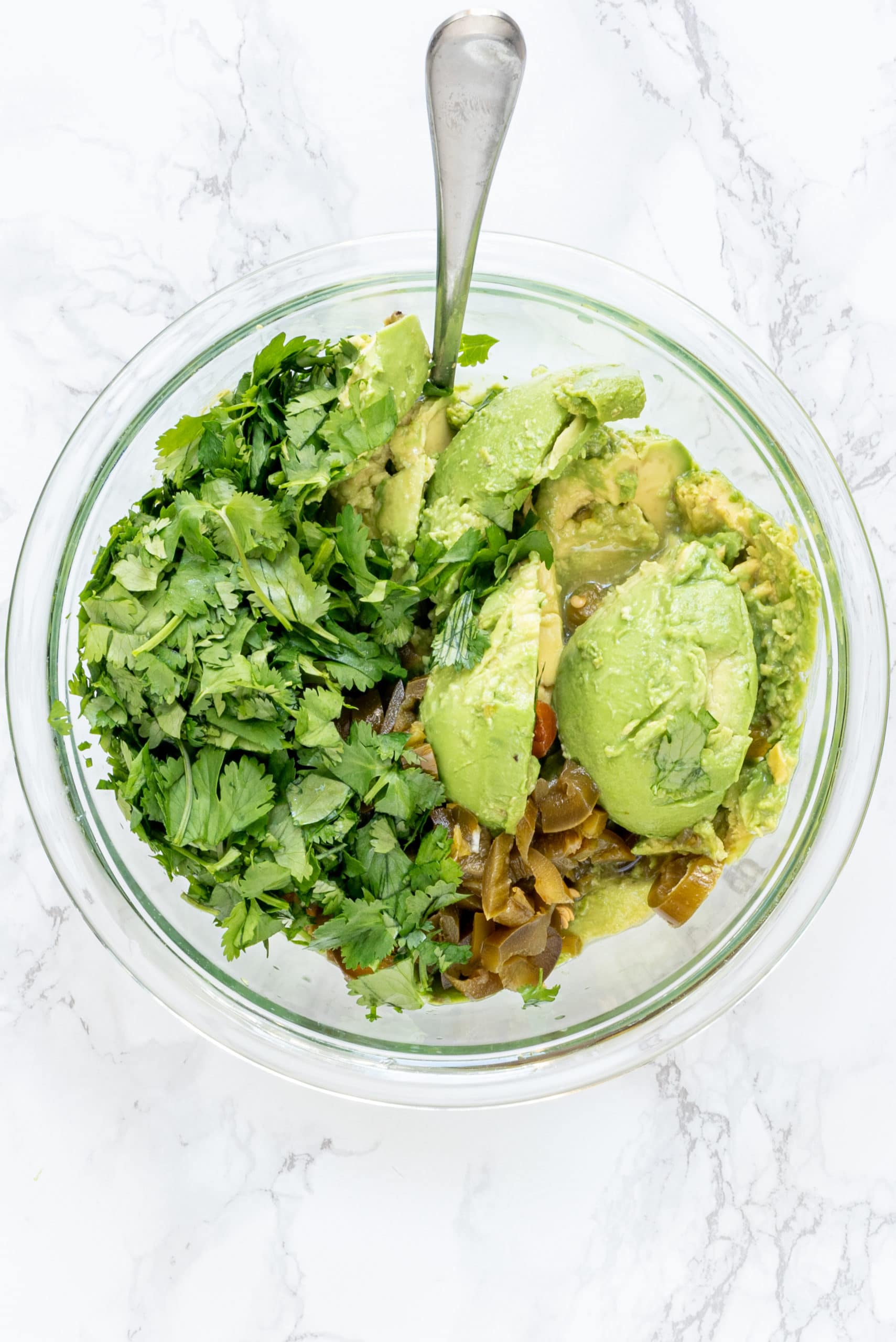 A glass bowl of mashed avocados.