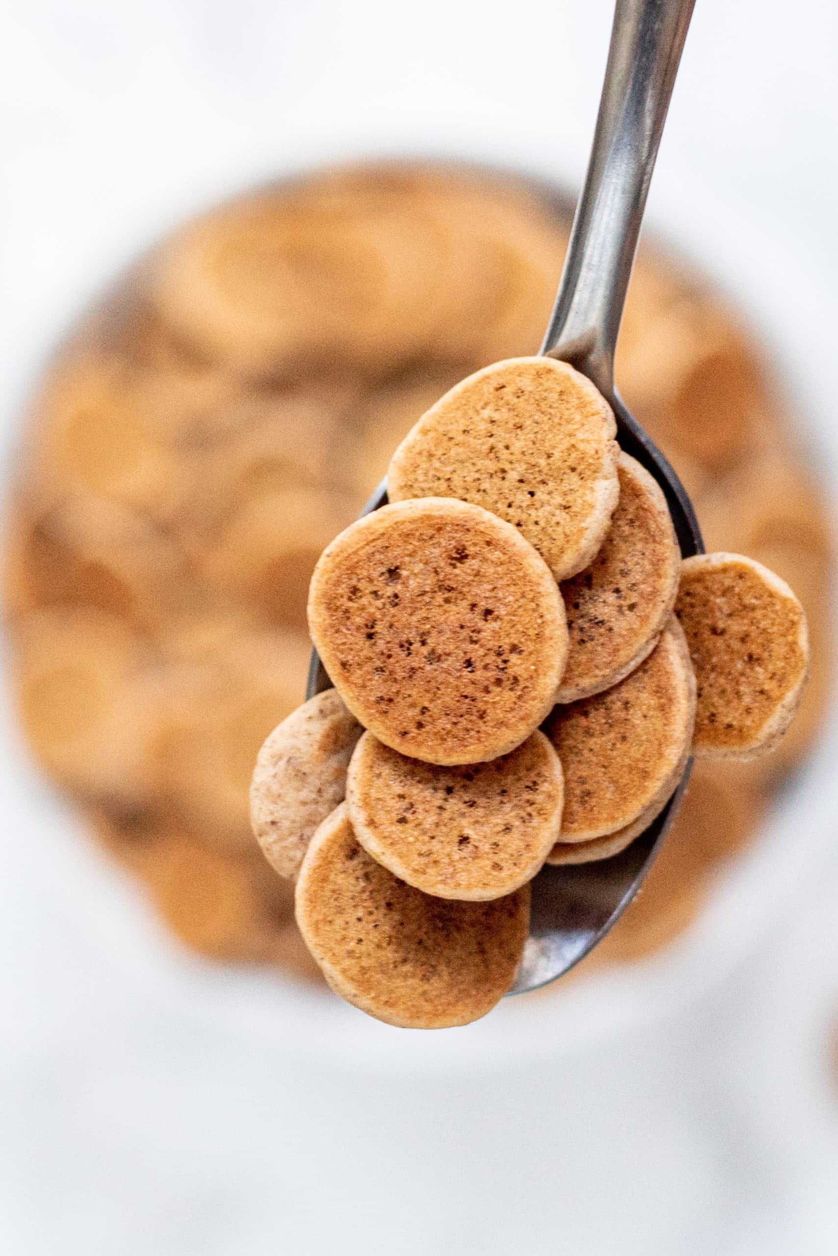 A silver spoon holding multiple mini pancakes.