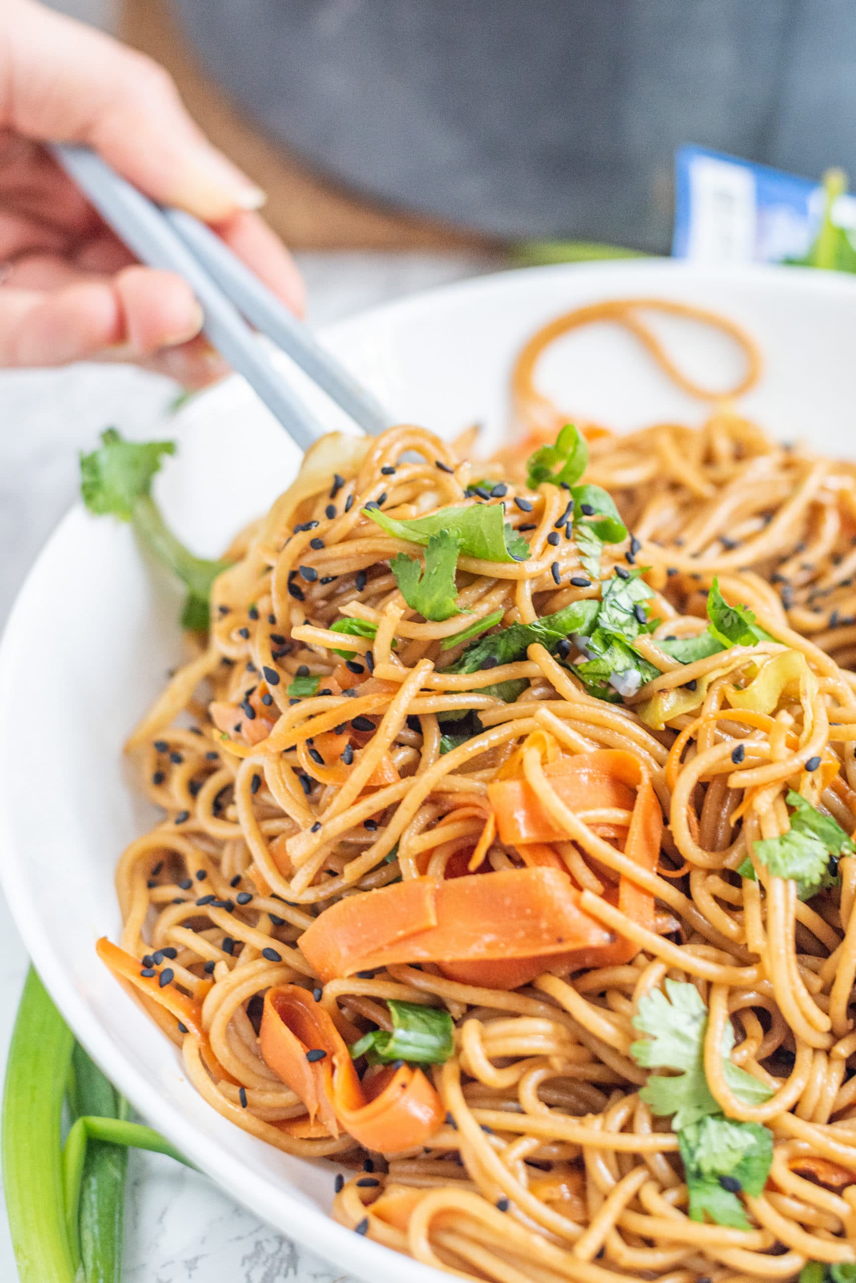 A white bowl filled with pad thai and a set of chopsticks.