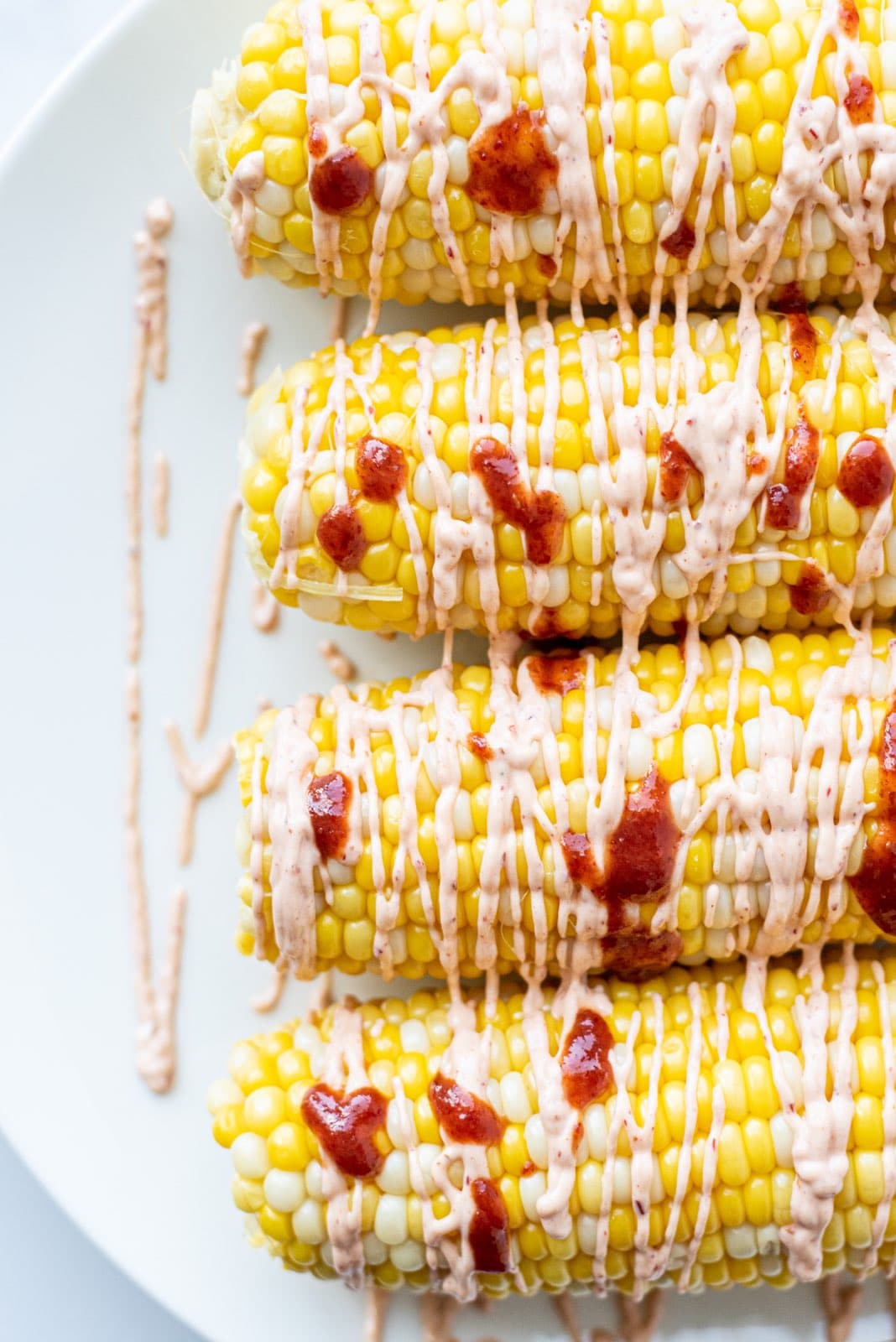 Four ears of corn topped with hot sauce and spicy cashew sauce.