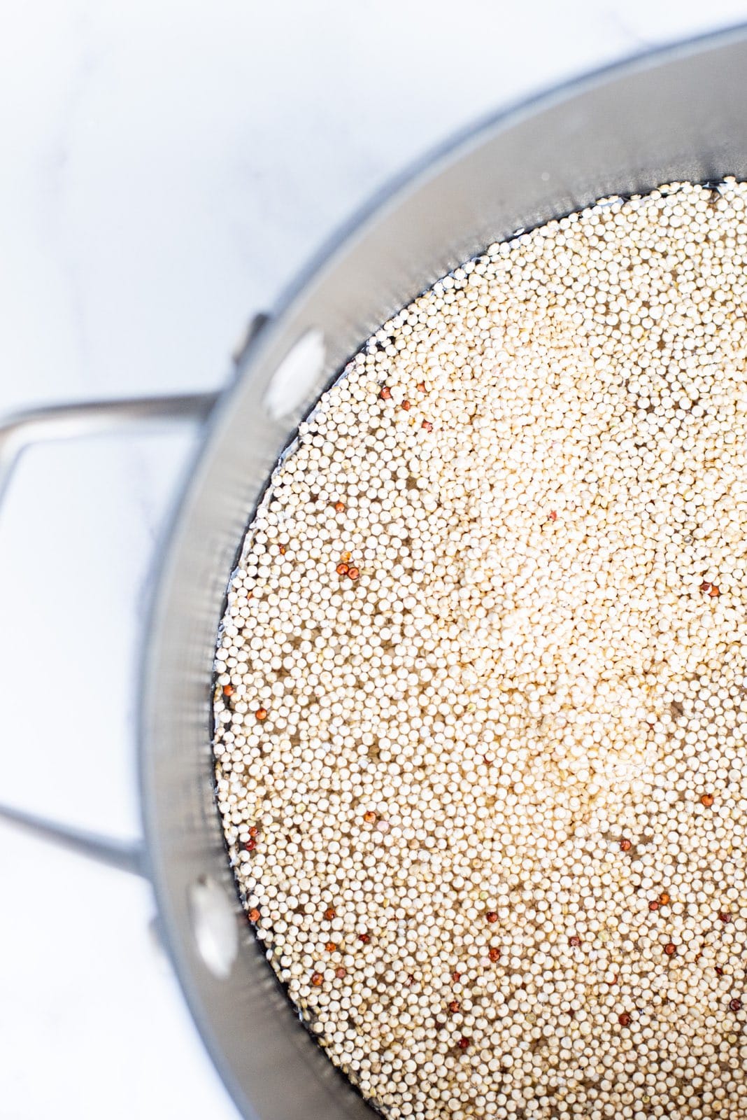 Half of a silver pot filled with water and quinoa.