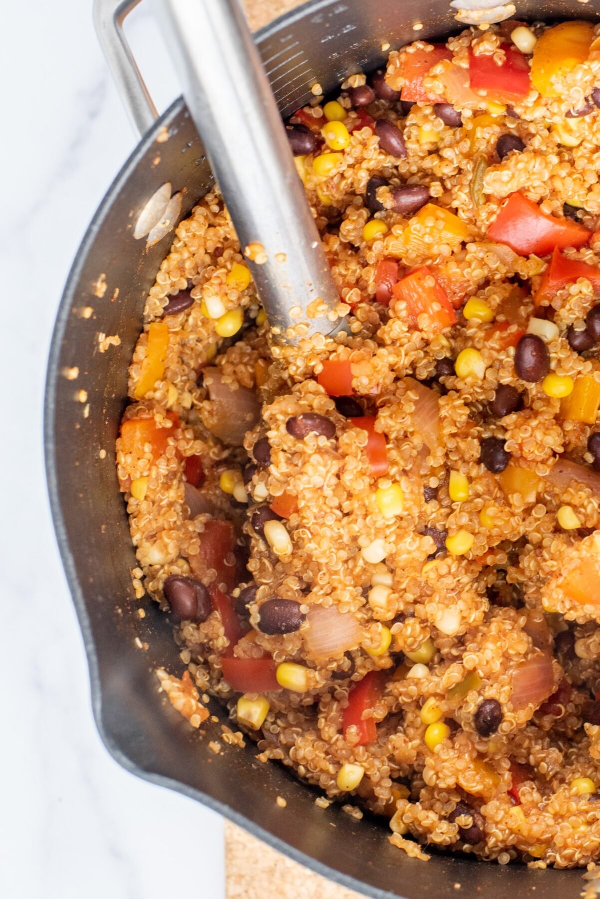 Vegan One-Pot Mexican Quinoa close up in a large silver pot with a large silver spoon sticking out of the pot.