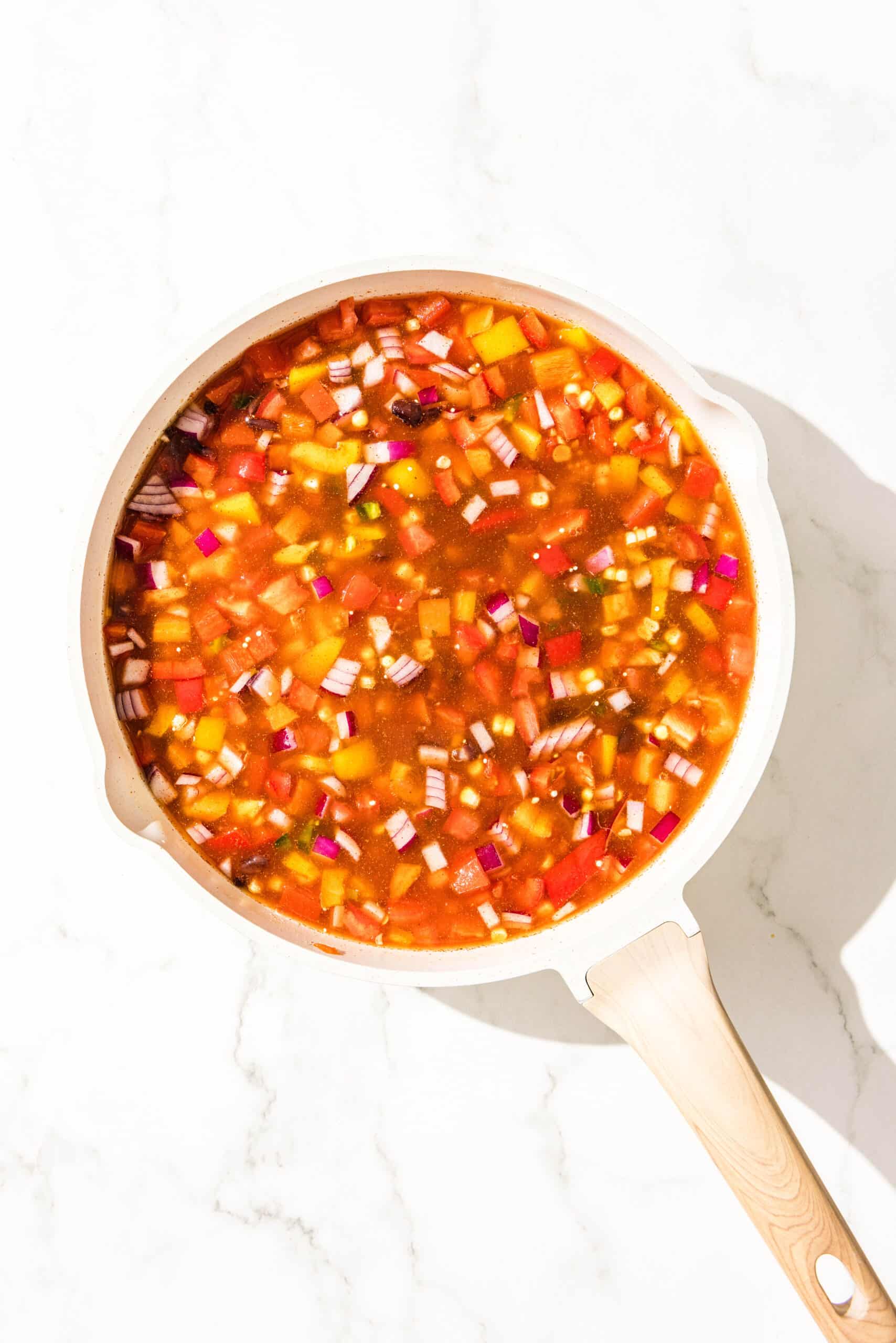 A large white pot of one pot mexican quinoa mixed and ready to be cooked.