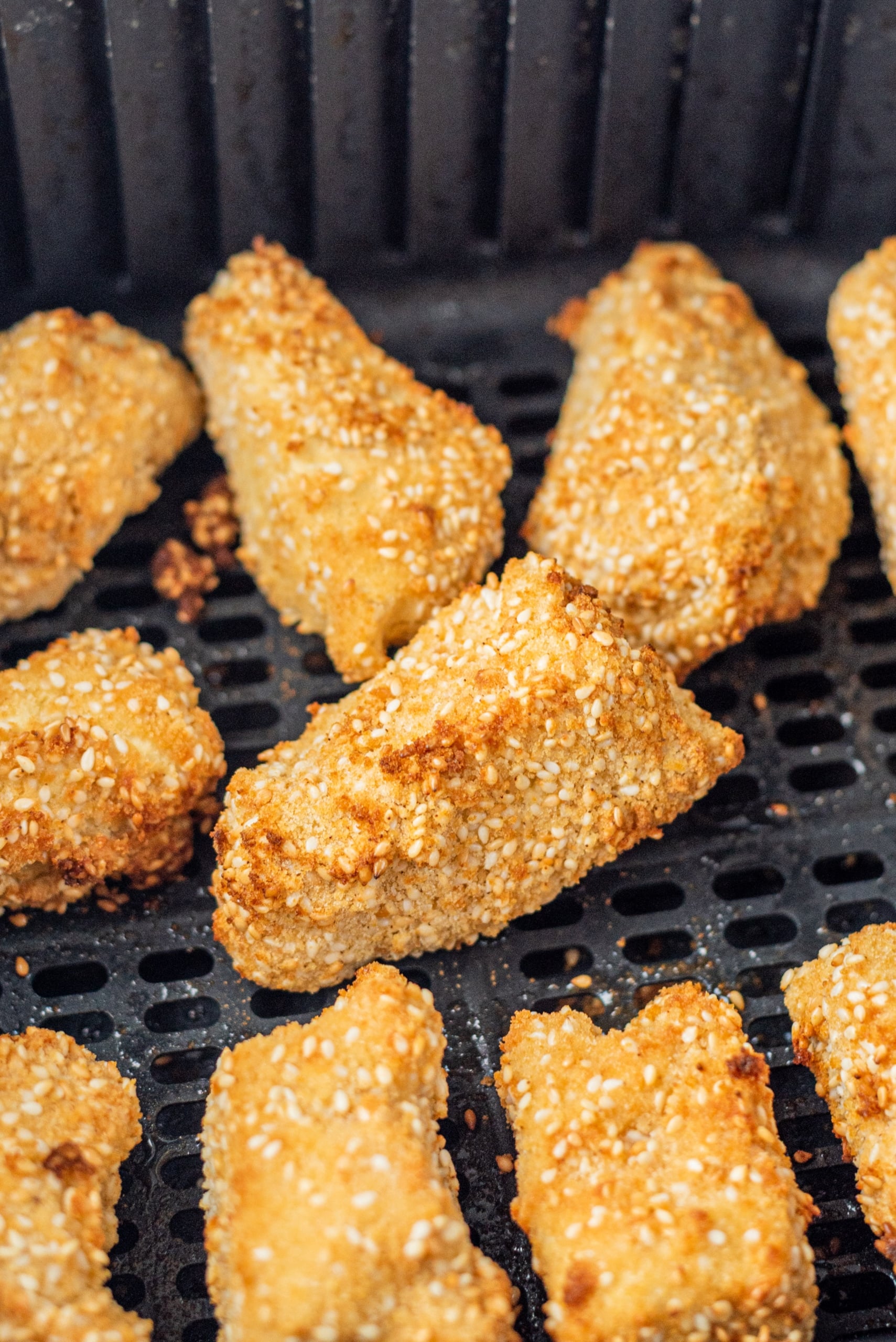 An air-fryer basket filled with crispy tofu nuggets.