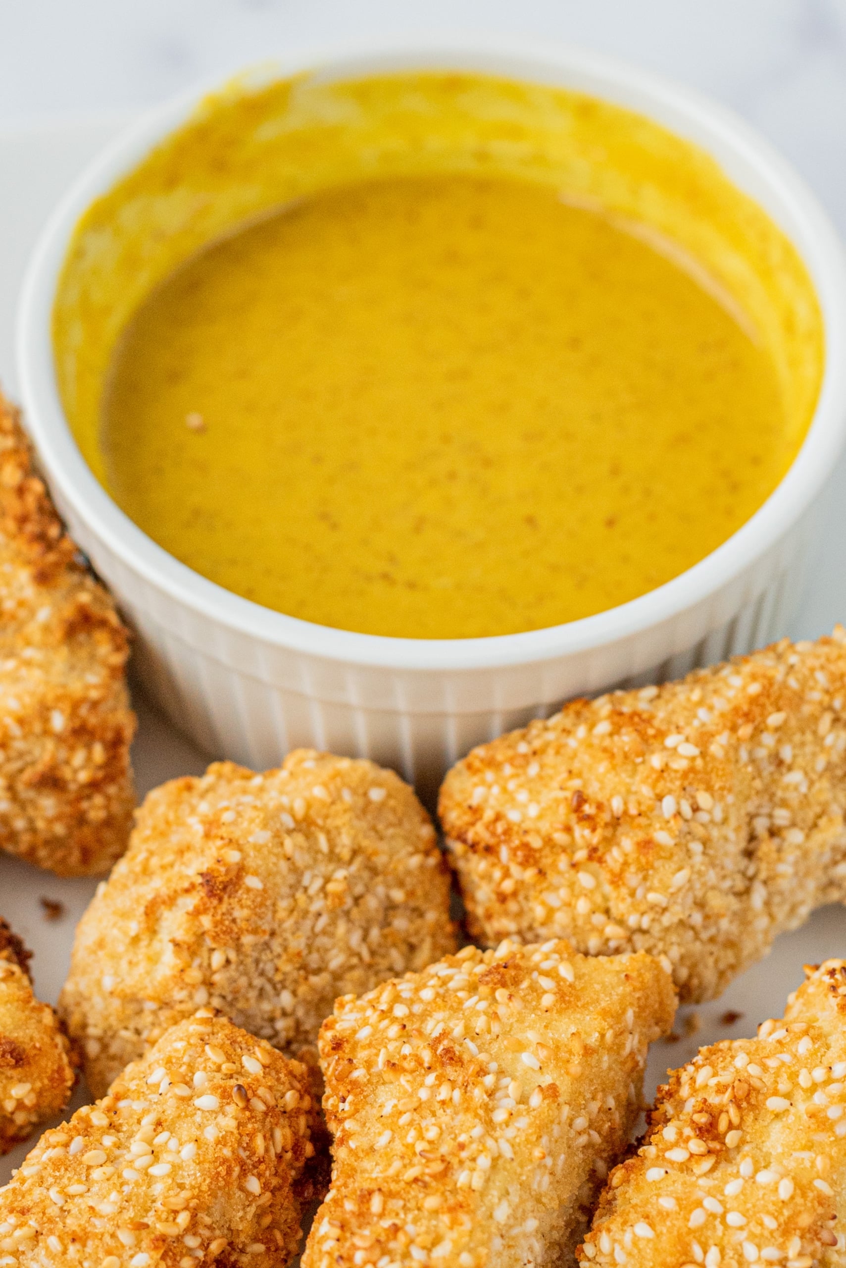 A plate of tofu tenders on it and a bowl of honey mustard.