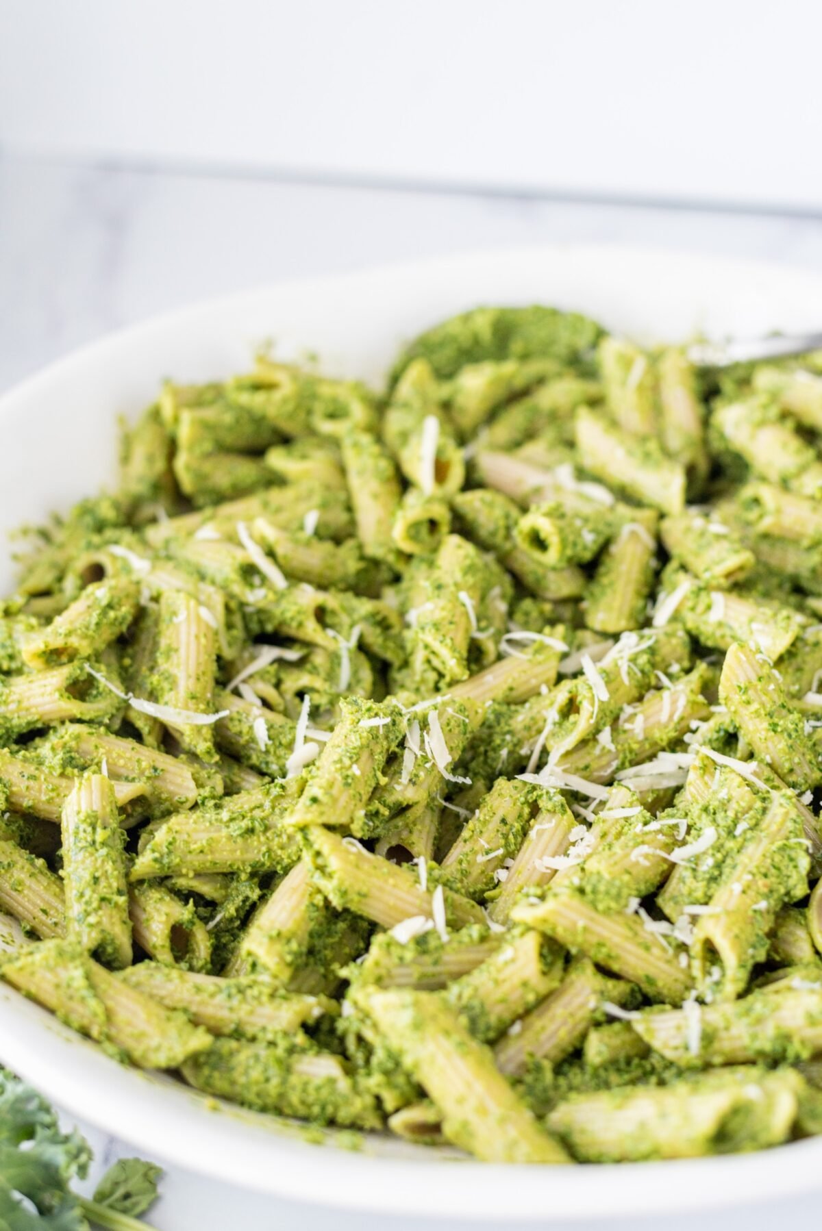 A close up of a white bowl filled with pesto pasta.