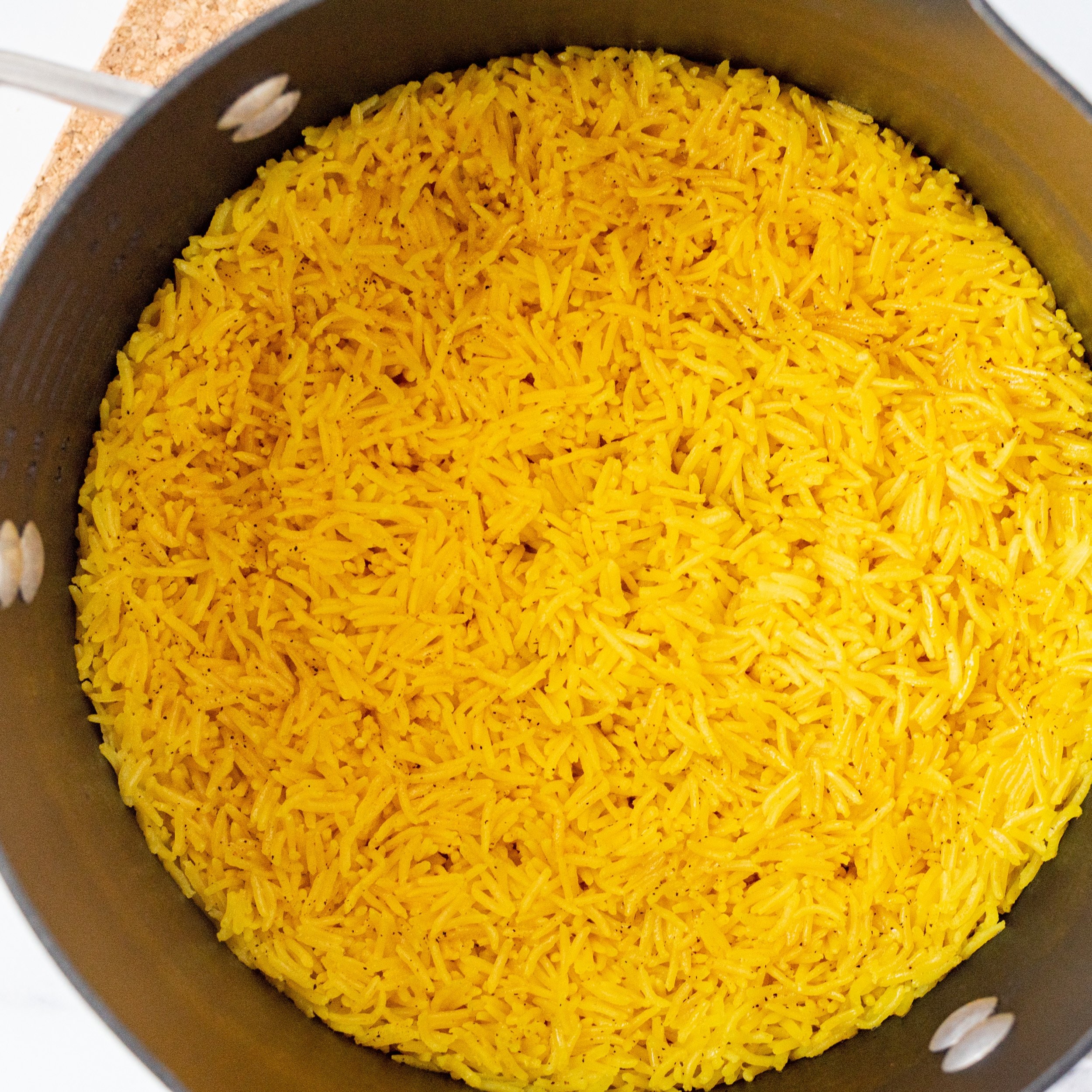 A black pot filled with cooked yellow rice.