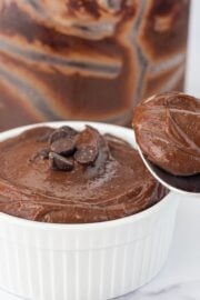 A bowl of chocolate pudding topped with chocolate chips and a spoon with a bite of pudding on it.