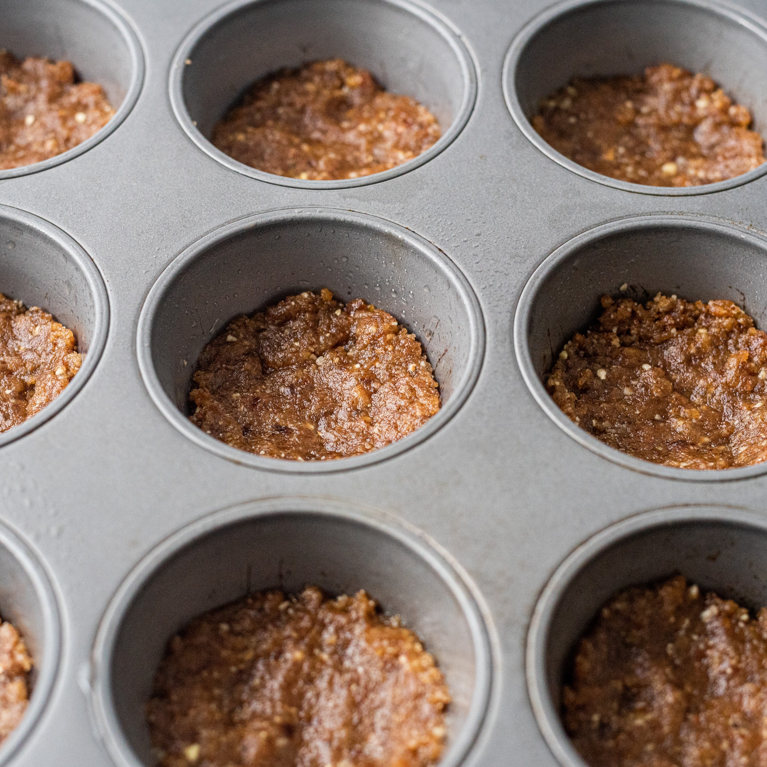 A muffin tin with crust pressed into the muffin cups.