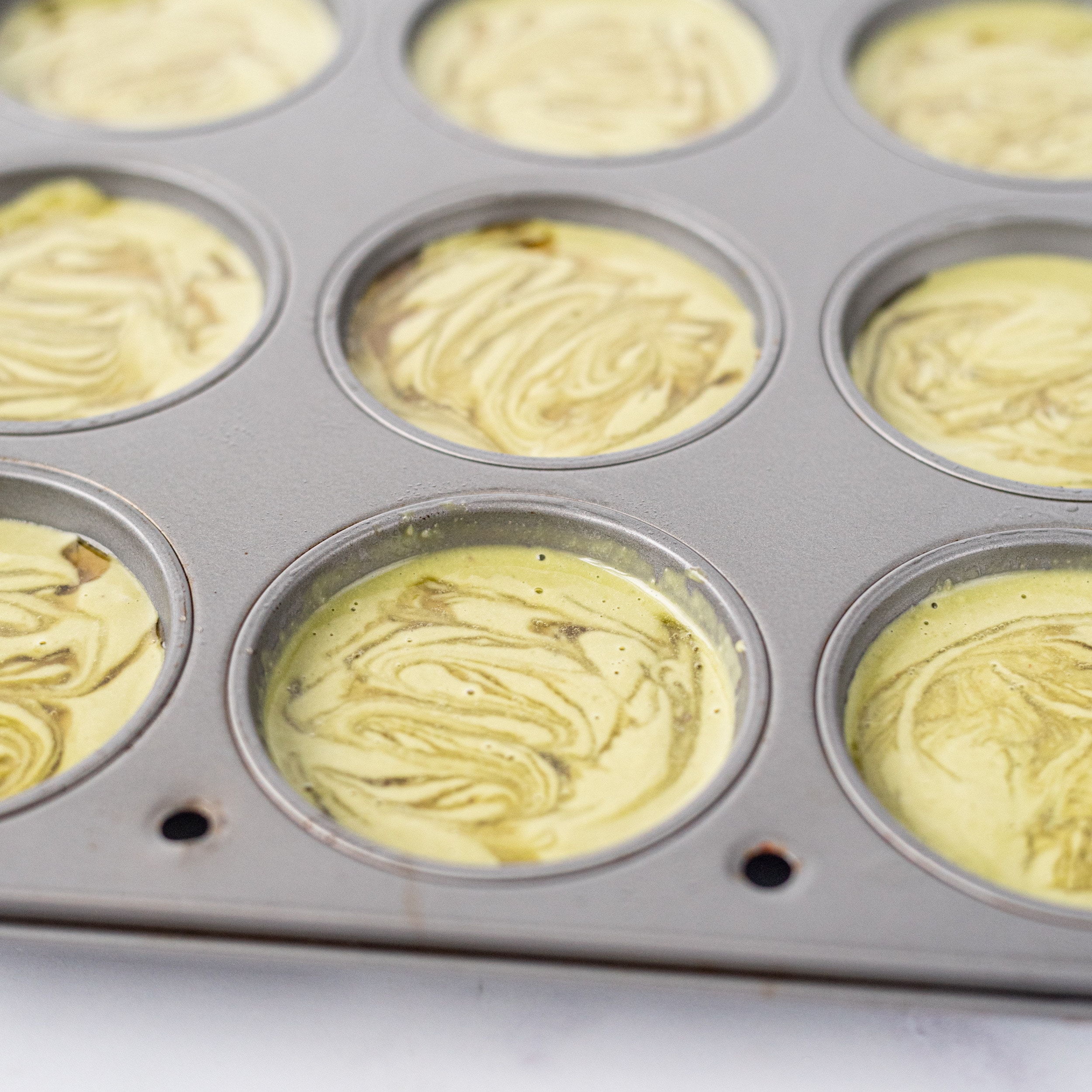 A muffin tin filled with matcha cheesecakes.