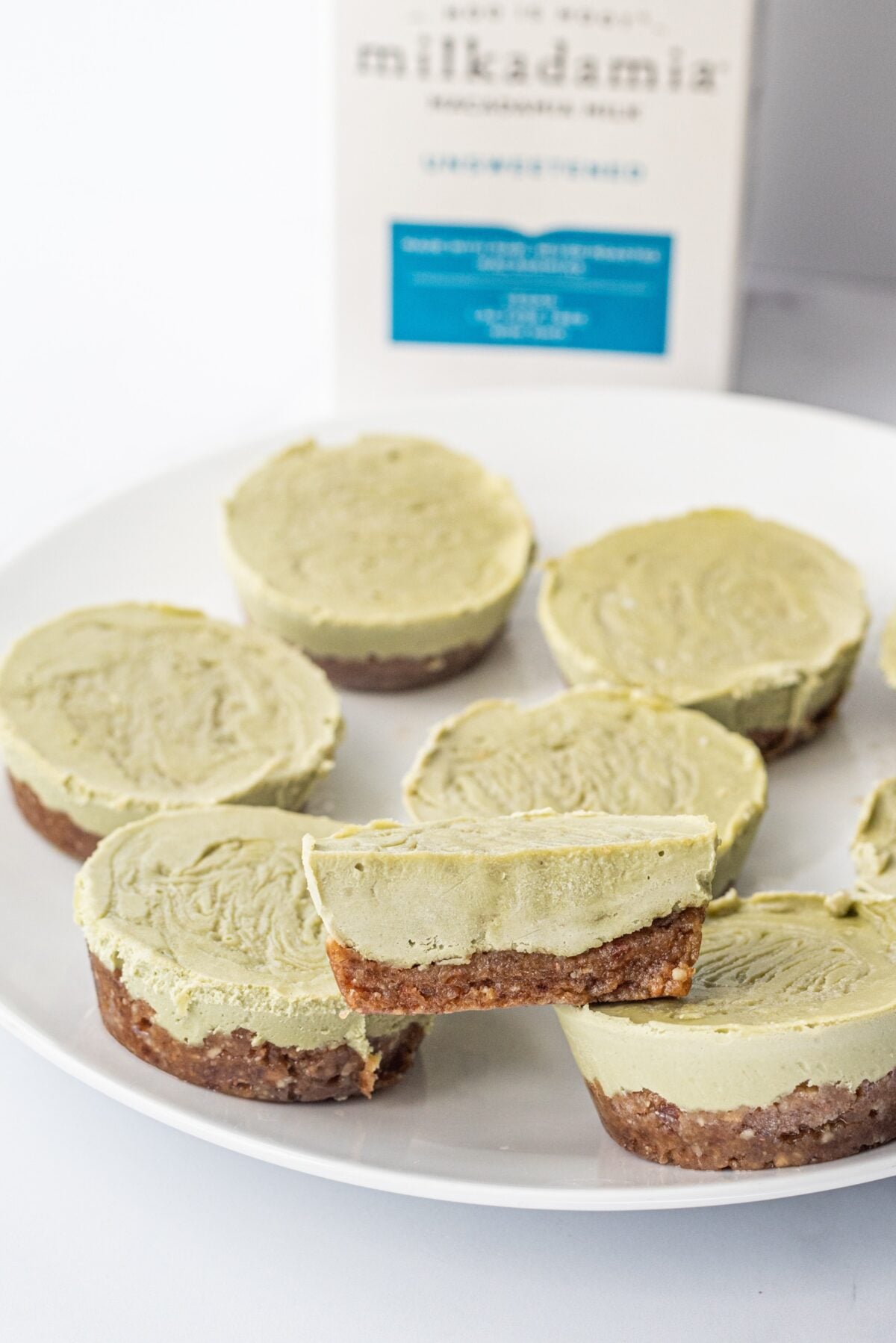 A plate of mini matcha cheesecakes and a carton of macadamia nut milk.