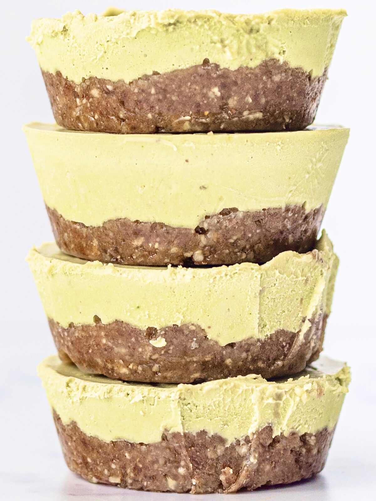 Four no bake matcha cheesecakes stacked on each other.