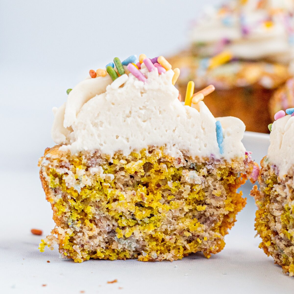 A funfetti muffin with frosting and sprinkles cut in half.