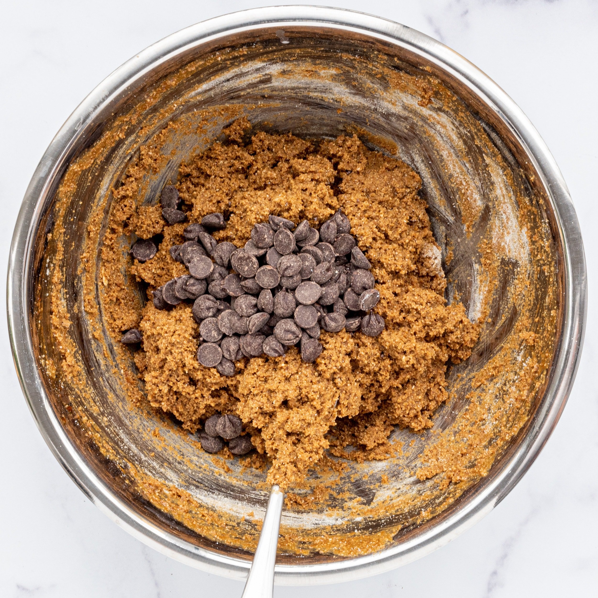 A silver bowl filled with pumpkin cookie dough and chocolate chips in the center.
