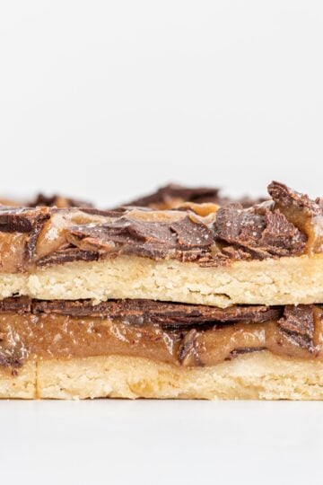 Two Vegan Gluten-Free Twix Bars stacked on top of each other with a few bars behind them in the background.