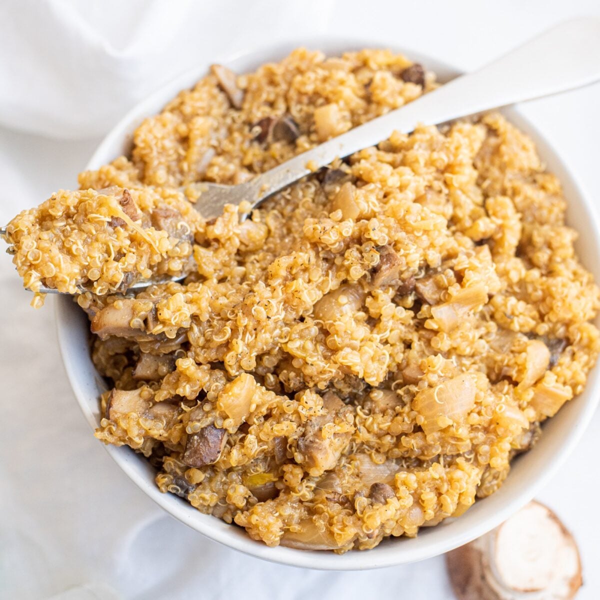 A bowl of Vegan One Pot Mushroom Quinoa Risotto and a metal spoon in the bowl.