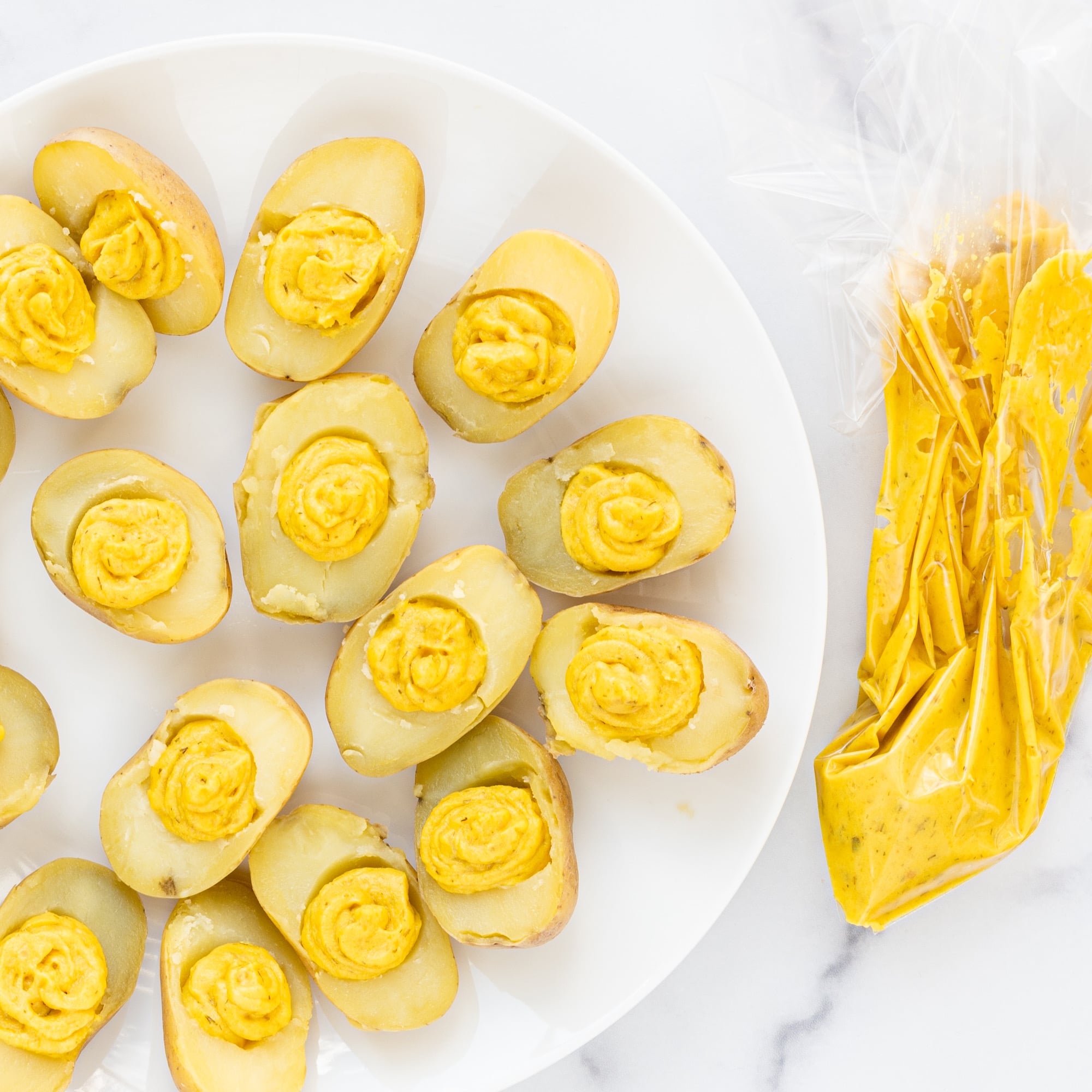 A plate of vegan deviled eggs made from potatoes and a bag of potato filling.