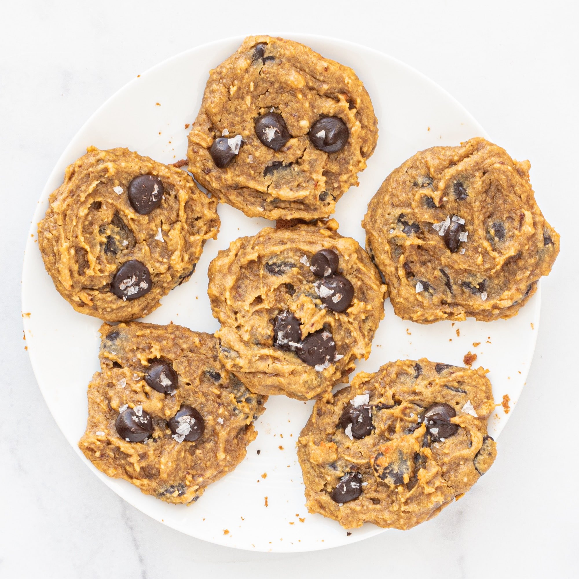 Five Vegan Chickpea Chocolate Chip Cookies sprinkled with sea salt on a white plate.