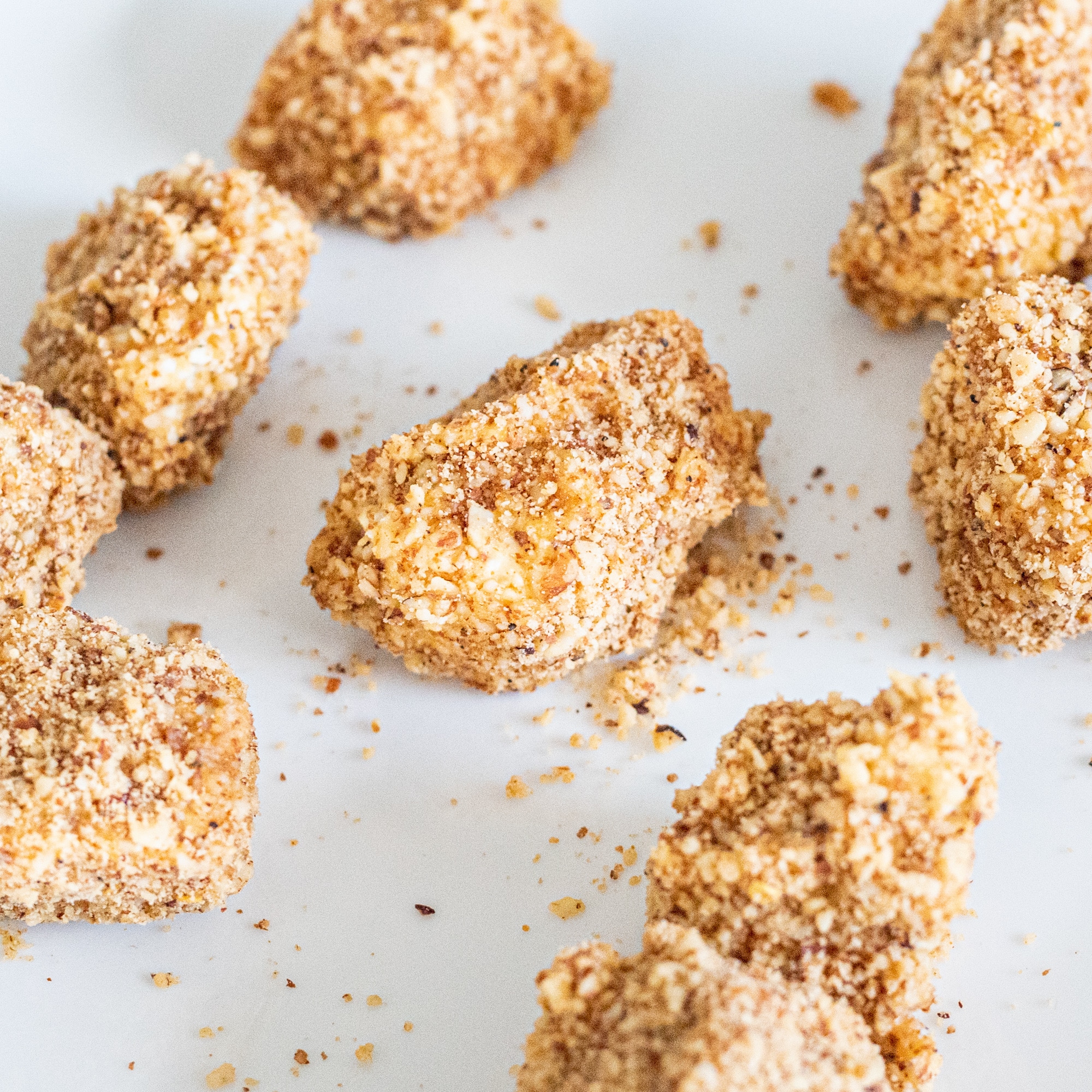 Tofu poppers coated in breadcrumbs on parchment paper.