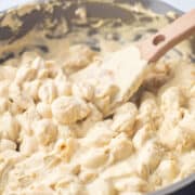 A pan filled with white cheddar mac and cheese and a spatula.