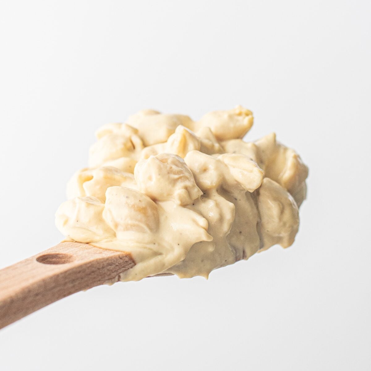 A wooden spoon with mac and cheese on it.