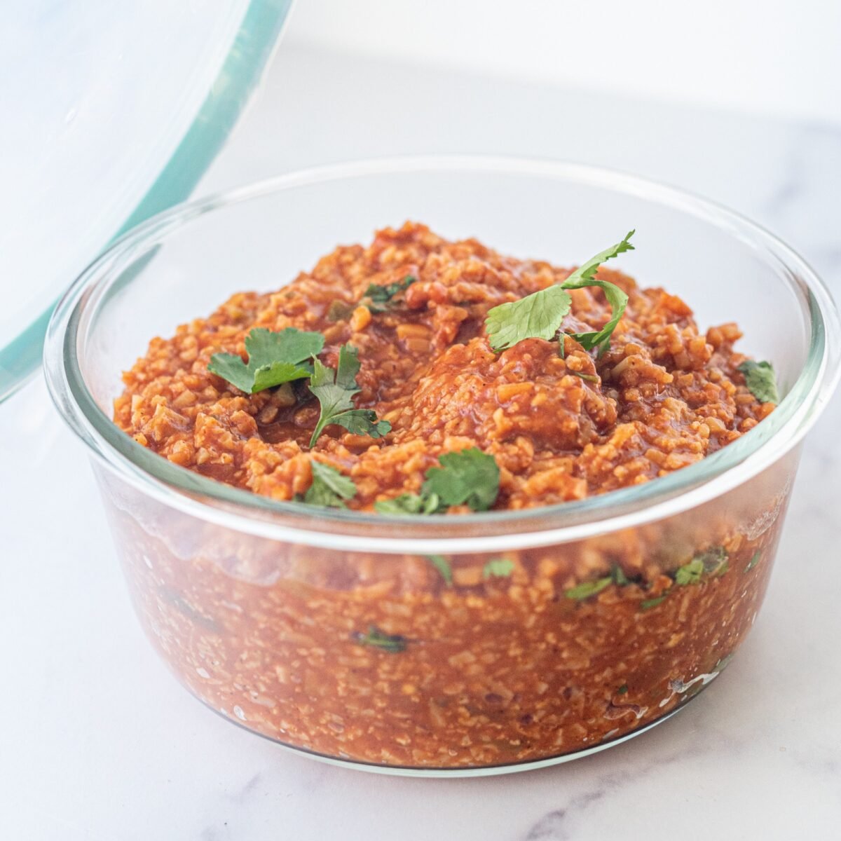 A glass dish filled with one pan creamy vegan mexican cauliflower rice garnished with fresh cilantro.