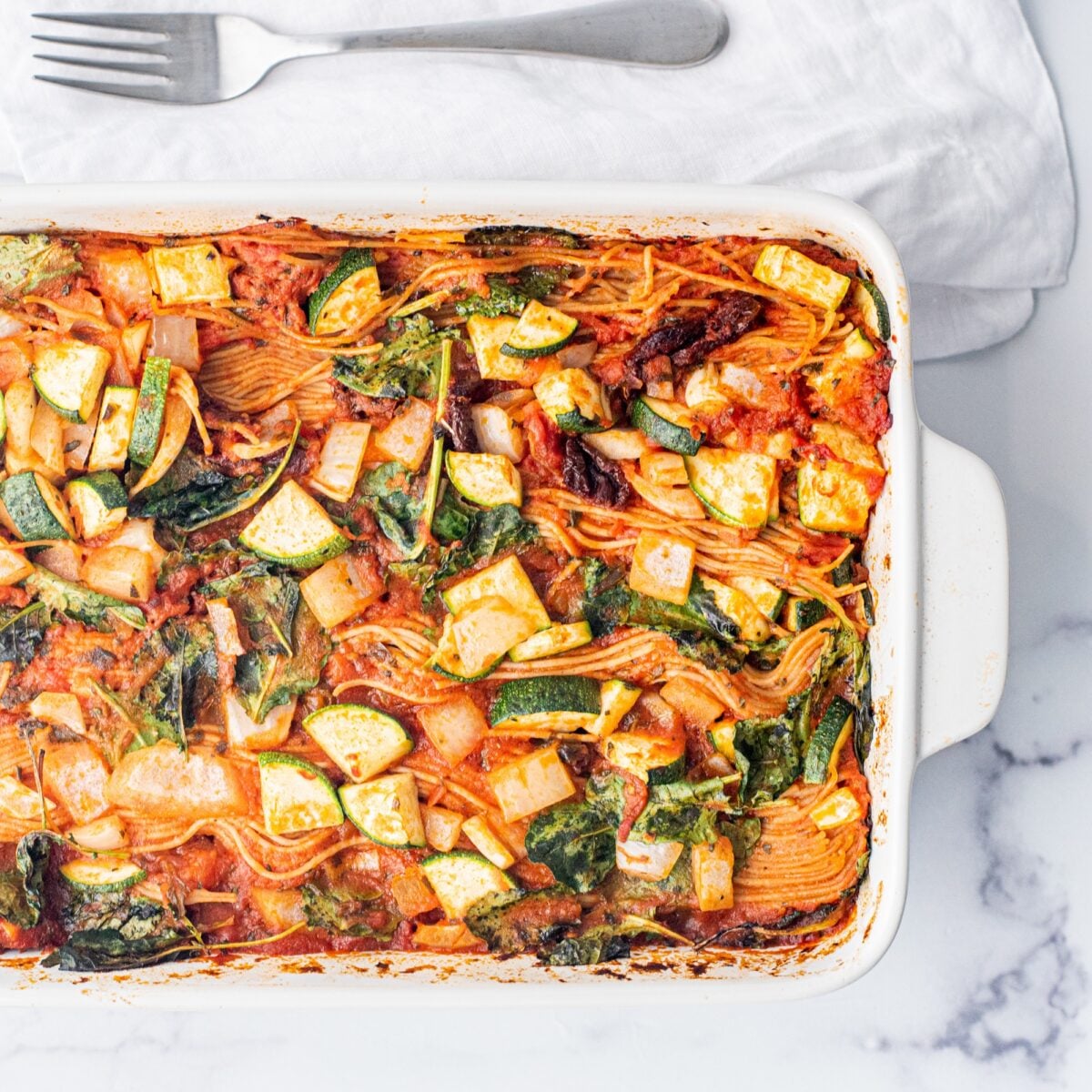 A 9x13 white casserole dish filled with baked spaghetti.