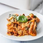 A white plate with a scoop of baked spaghetti on it.