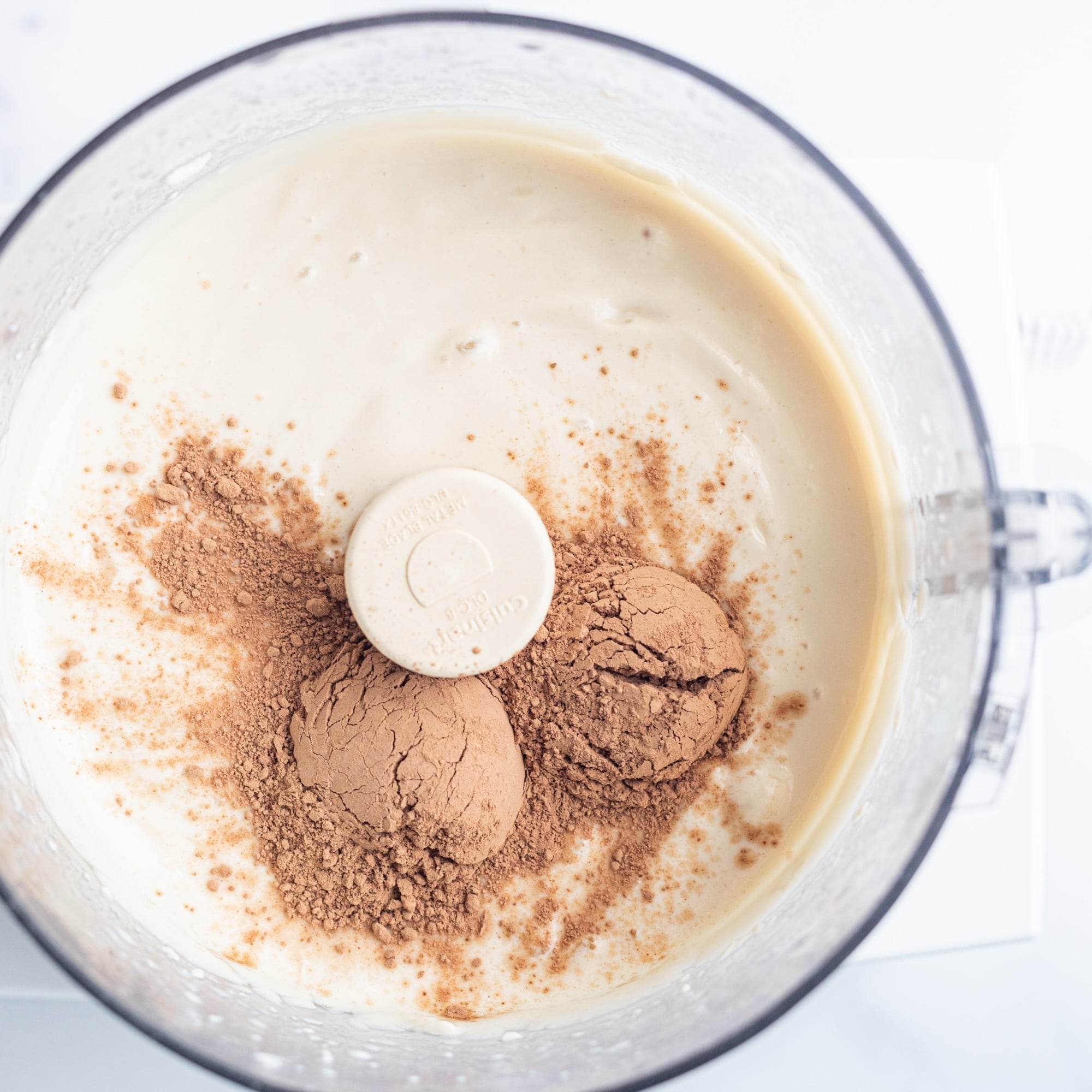 A food processor filled with blended silken tofu and cacao powder.