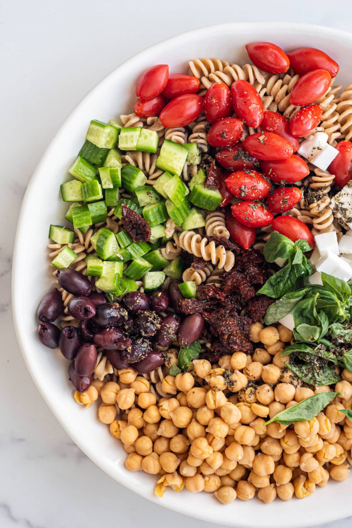Birds eye view of a large white bowl of vegan greek pasta salad.