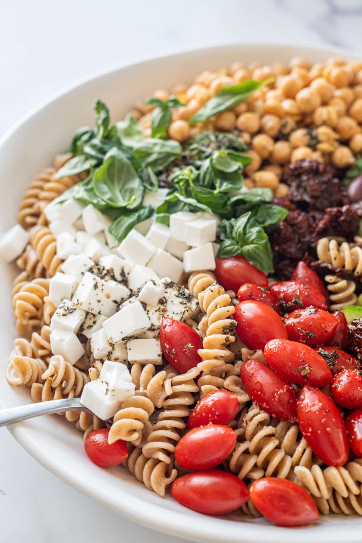 A large white bowl of vegan greek pasta salad.