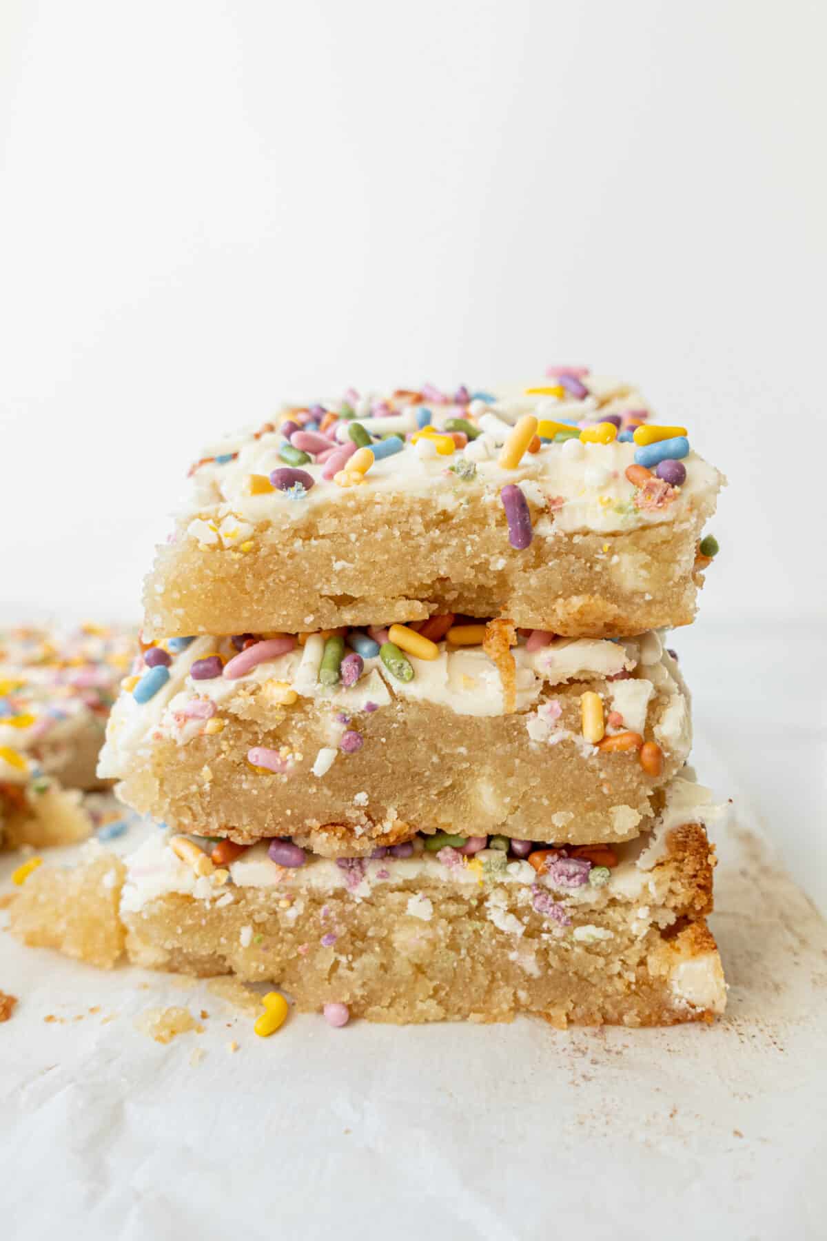 Three Vegan Gluten-free Sugar Cookie Bars stacked on top of each other with one in the background behind.