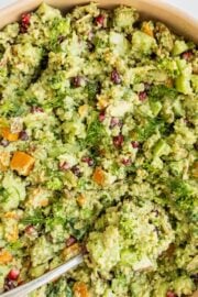 Quinoa broccoli salad in a large wooden bowl with a silver spoon in it.