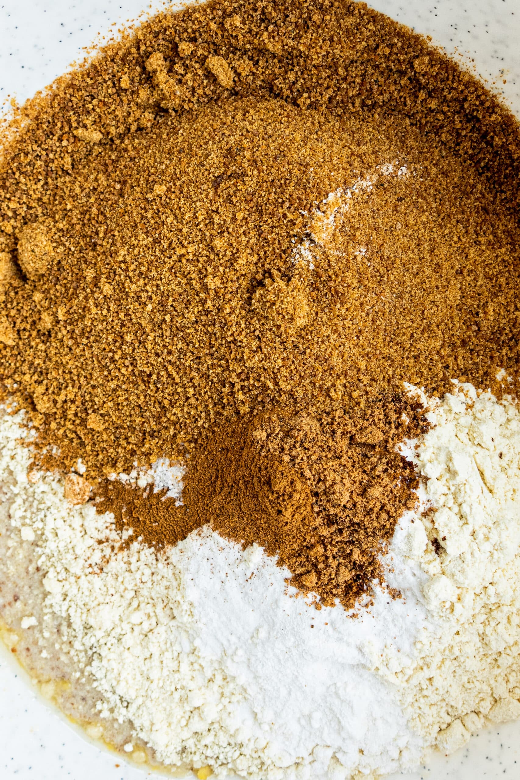 A large bowl filled with dry ingredients used in the carrot cake including coconut sugar, almond flour, and gluten-free flour.